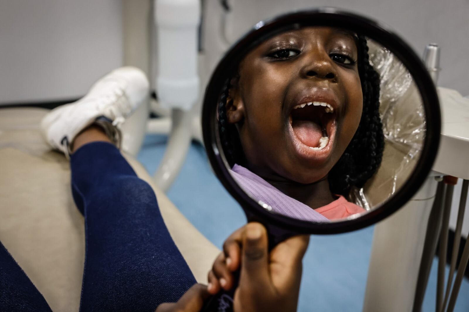 Etienne Bizimana, 5, checks her smile at the Sinclair Community College Midmark Dental Health Clinic on Monday, June 3, 2024. Refugee children from the Congo received dental care by dental hygiene students. JIM NOELKER/STAFF