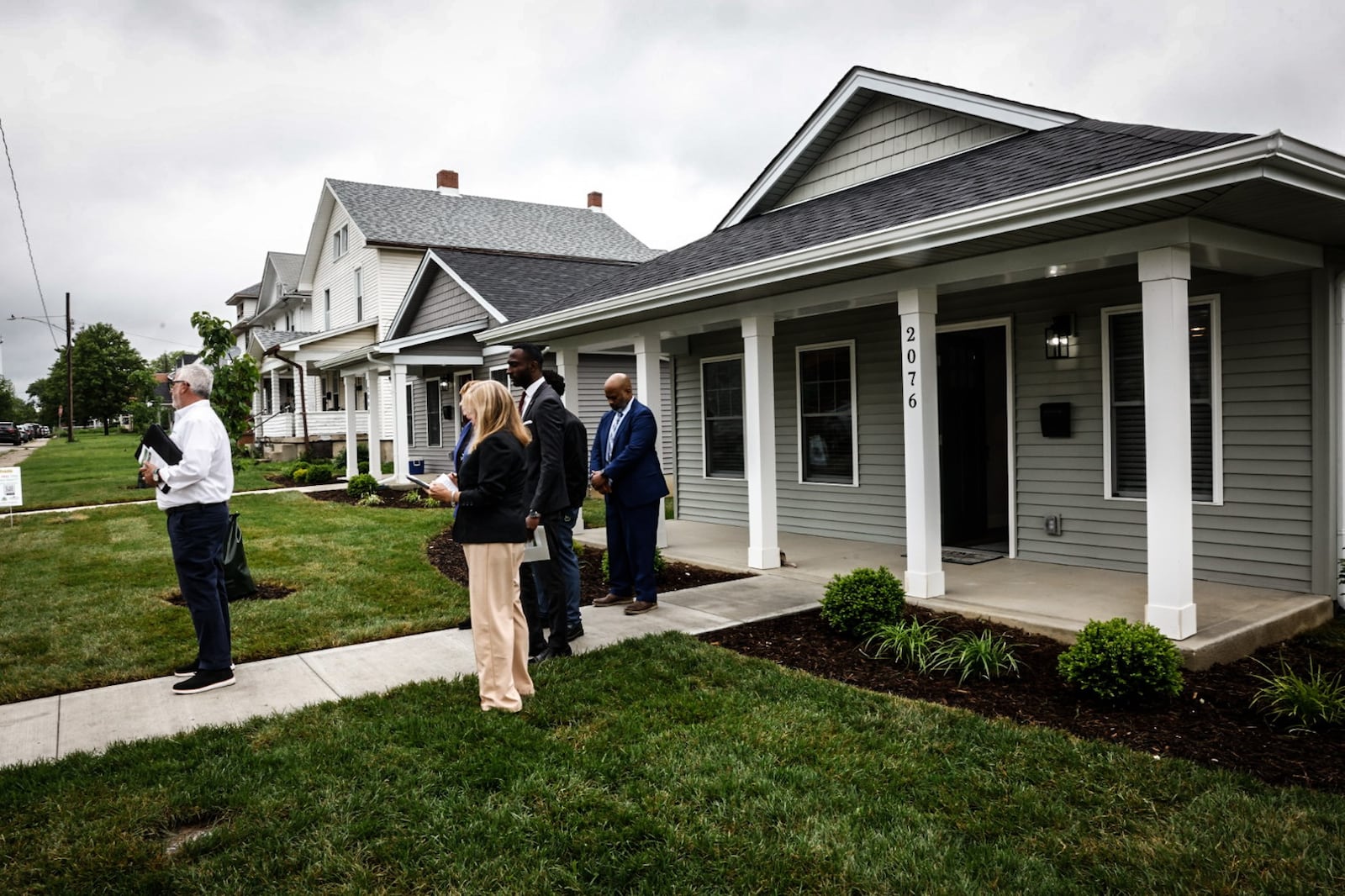 President of County Corp Steve Naas, left in white shirt, makes comments in May 2024 before touring three new homes built by Pathway to Homeownership which builds homes for first-time homebuyers. JIM NOELKER/STAFF