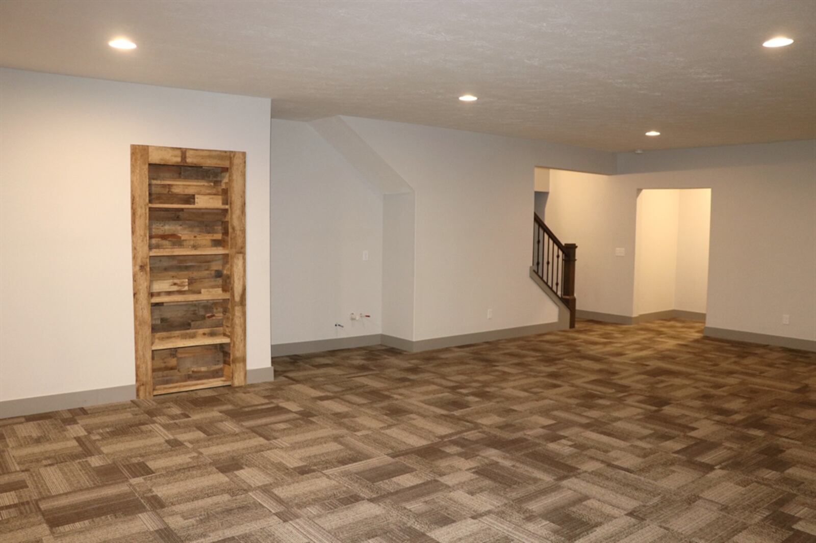 The recreation room has carpeting, a built-in bookcase and is plumbed for a wet bar near the stairwell. 