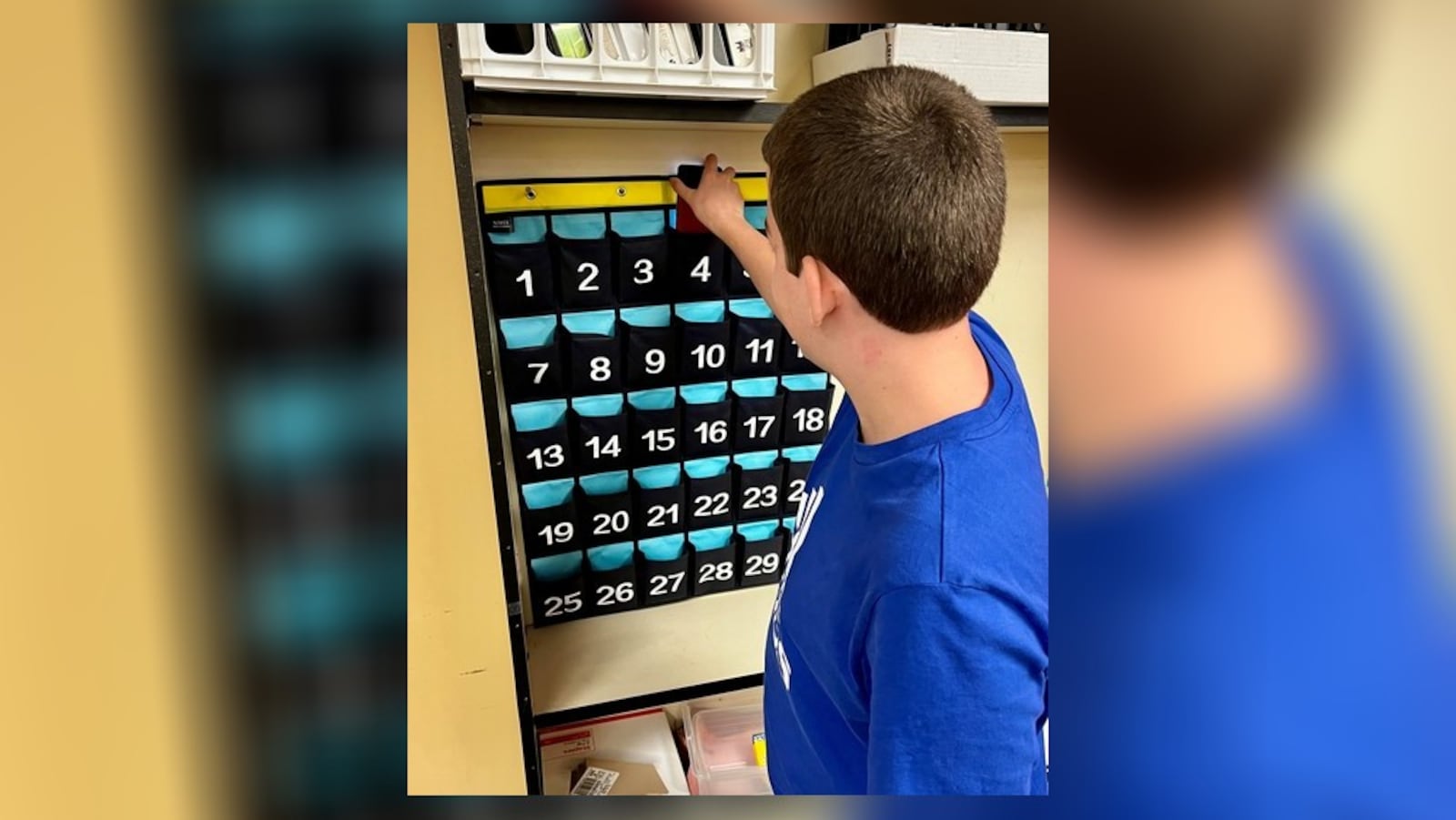 A Centerville High School student puts his cell phone in a classroom caddie Wednesday as the district started the 2024-25 school year. Centerville is among area school district banning student cell phone during school after updating personal communication device policy. CONTRIBUTED