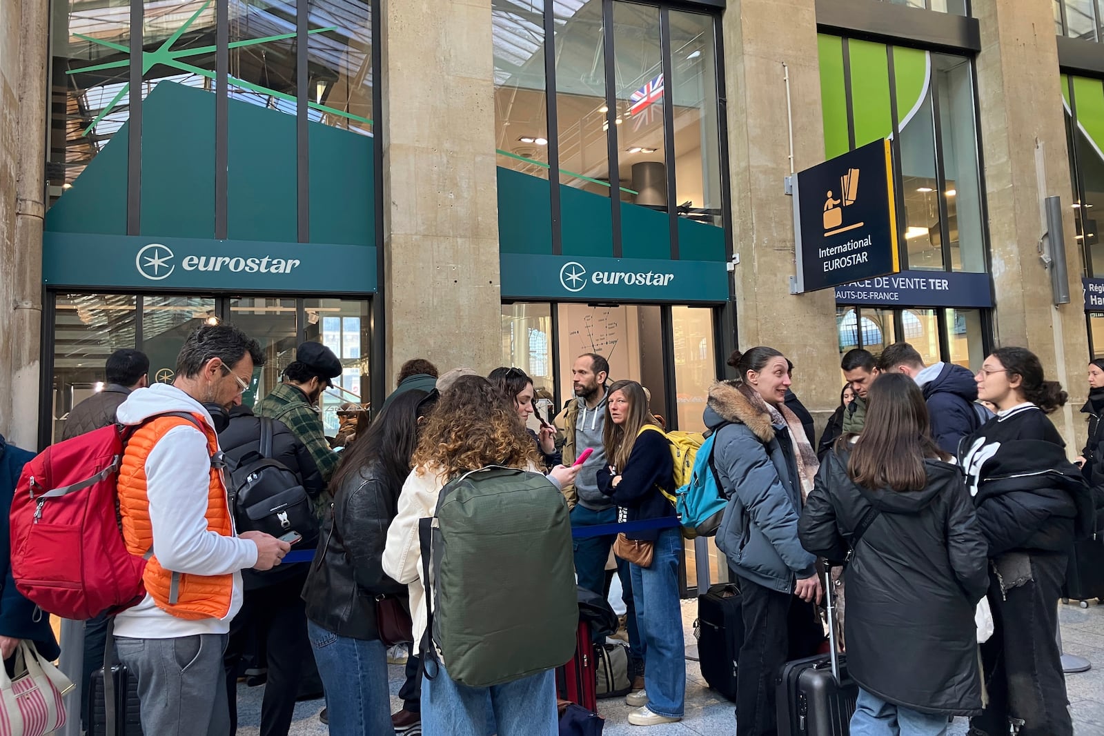 Travelers wait as Eurostar trains to London and all trains heading to northern France have been brought to a halt following the discovery of an unexploded bomb dating back to World War II near the tracks, Friday, March 7, 2025 at the Gare du Nord station in Paris. (AP Photo/Christophe Ena)