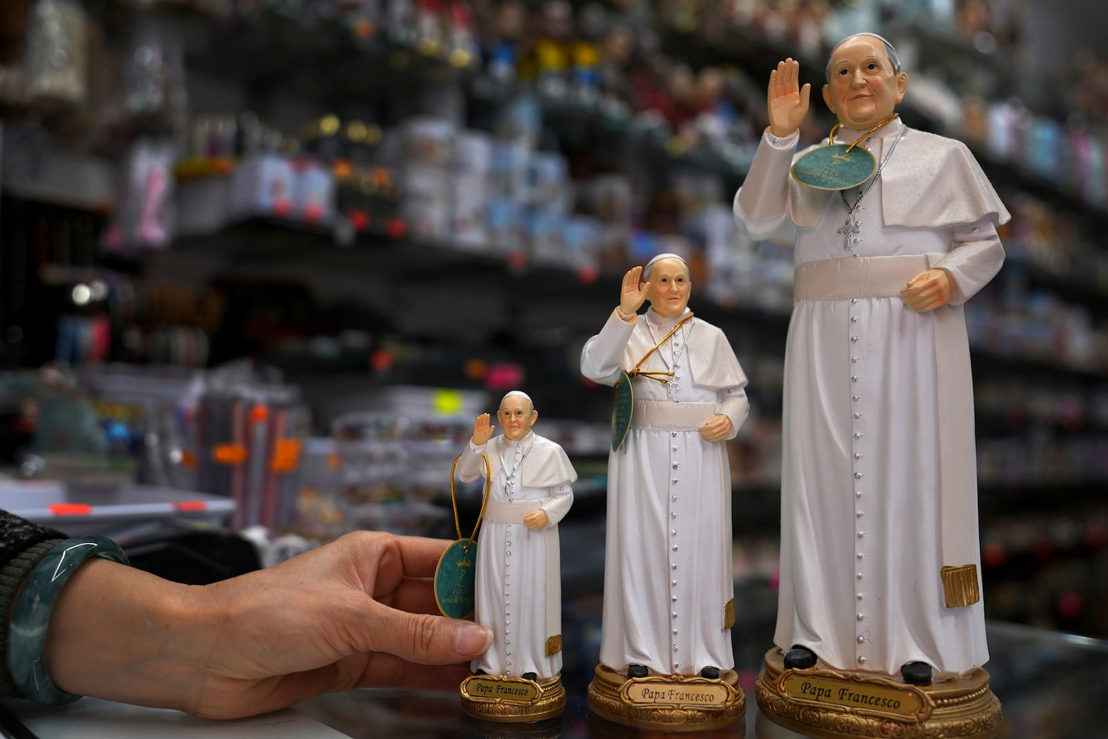 A shop worker arranges figurines of Pope Francis for a photograph in a souvenir shop in Rome, Thursday, Feb. 27, 2025. (AP Photo/Kirsty Wigglesworth)