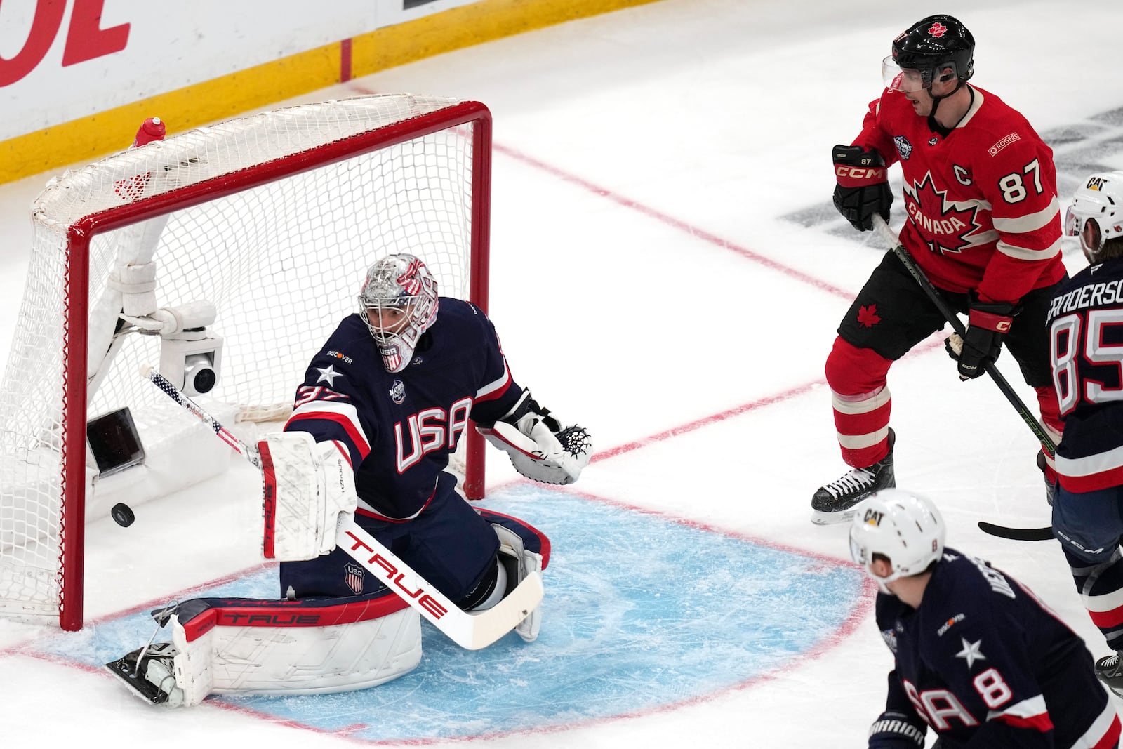 United States goalie Connor Hellebuyck, left, gives up a goal to Canada's Nathan MacKinnon, as Canada's Sidney Crosby (87) looks on, during the first period of the 4 Nations Face-Off championship hockey game, Thursday, Feb. 20, 2025, in Boston. (AP Photo/Charles Krupa)