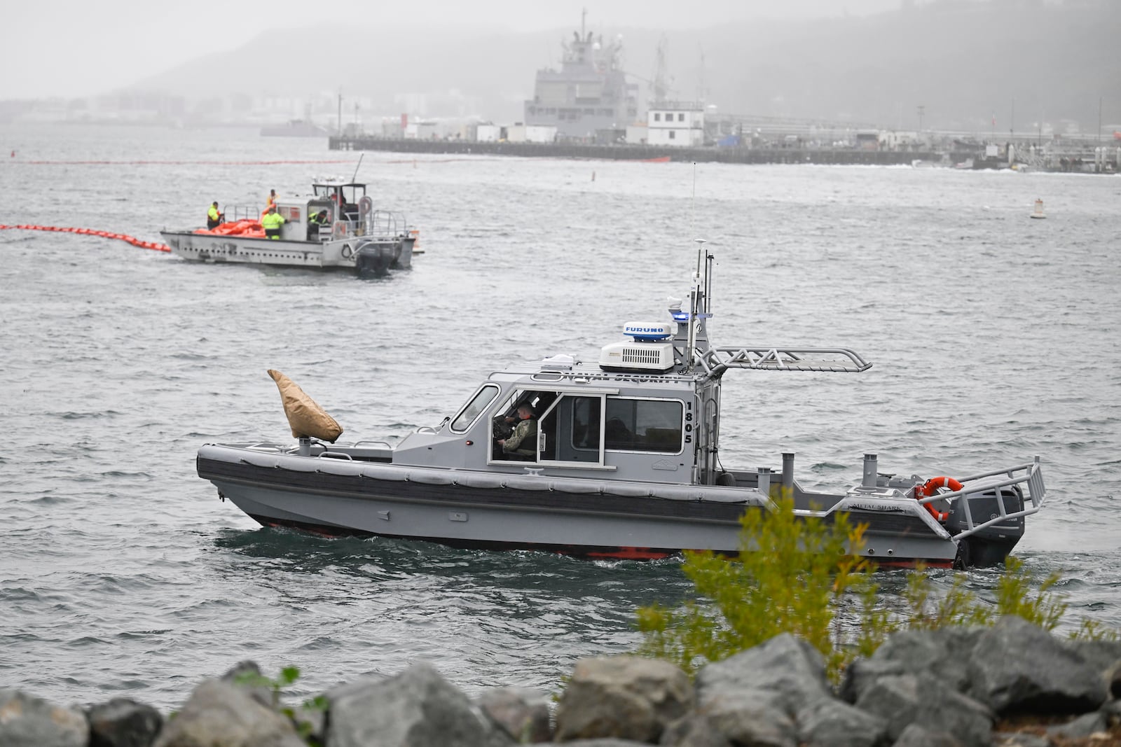 U.S. Navy boats work along the shore near Shelter Island after a U.S. Navy plane crashed into the San Diego Bay, Wednesday, Feb. 12, 2025, in San Diego. (AP Photo/Denis Poroy)