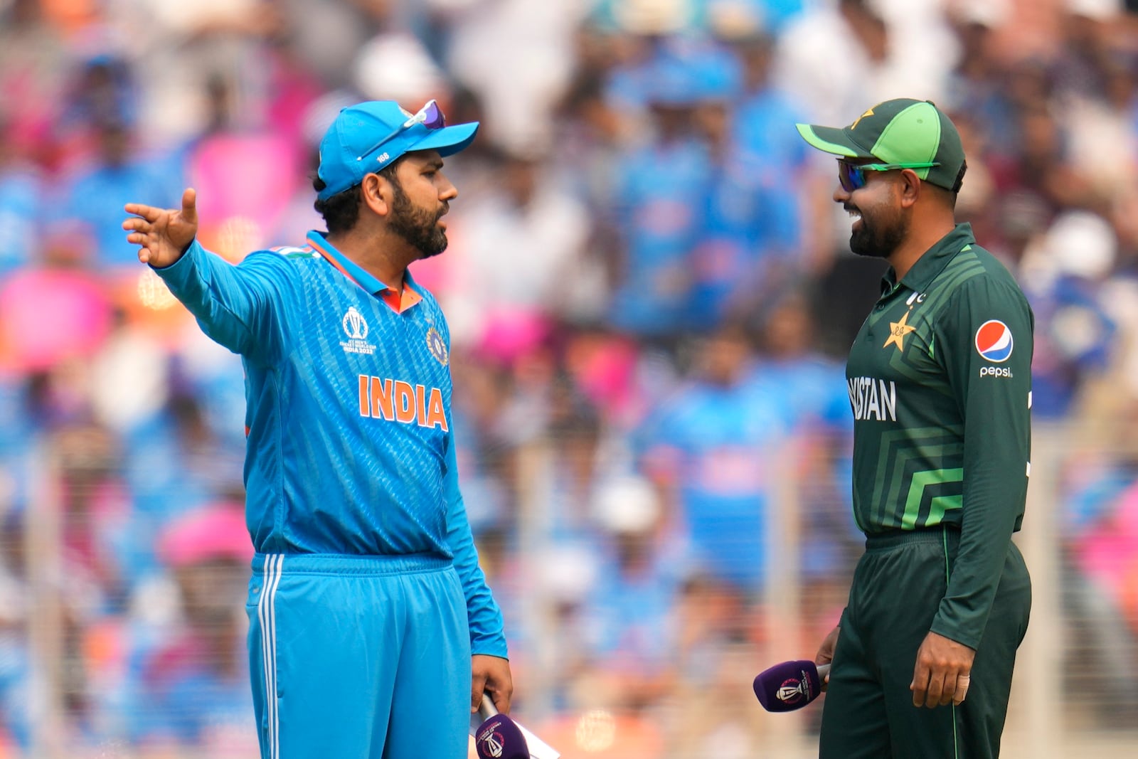 India's captain Rohit Sharma, left and Pakistan's captain Babar Azam talk before the coin toss during the ICC Men's Cricket World Cup match between India and Pakistan in Ahmedabad, India, Oct. 14, 2023. (AP Photo/Aijaz Rahi, File)