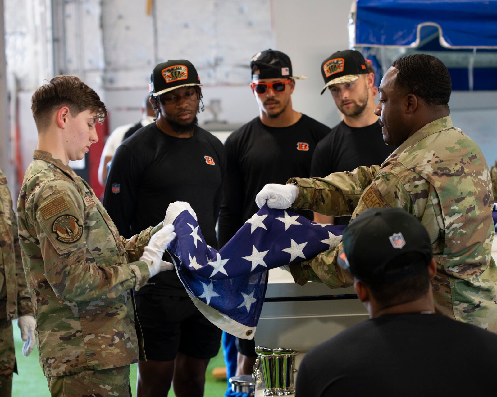 Cincinnati Bengals players get a lesson in flag folding from the Honor Guard during a visit to the base. U.S. Air Force photo / Jaima Fogg