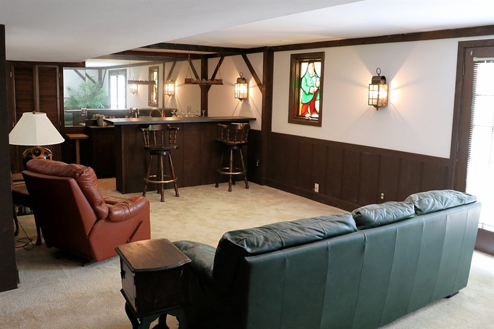 The tavern-style décor continues in the lower level with the combined family room and recreation room. Wood paneling covers half the wall space and wood beams accent the rest.