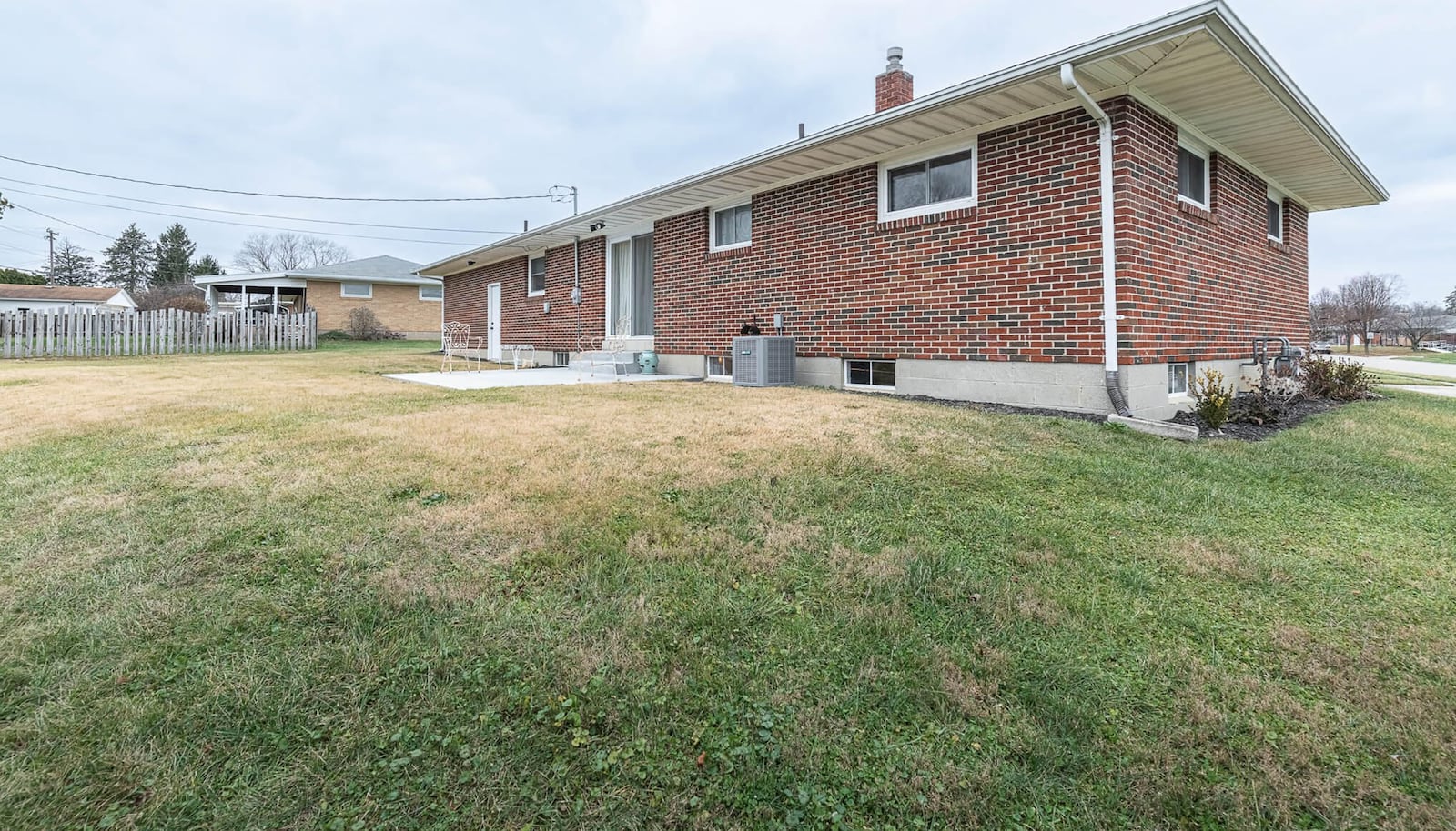 The rear of this all-brick ranch has a concrete patio, sliding glass door and exterior door leading to the two-car garage.