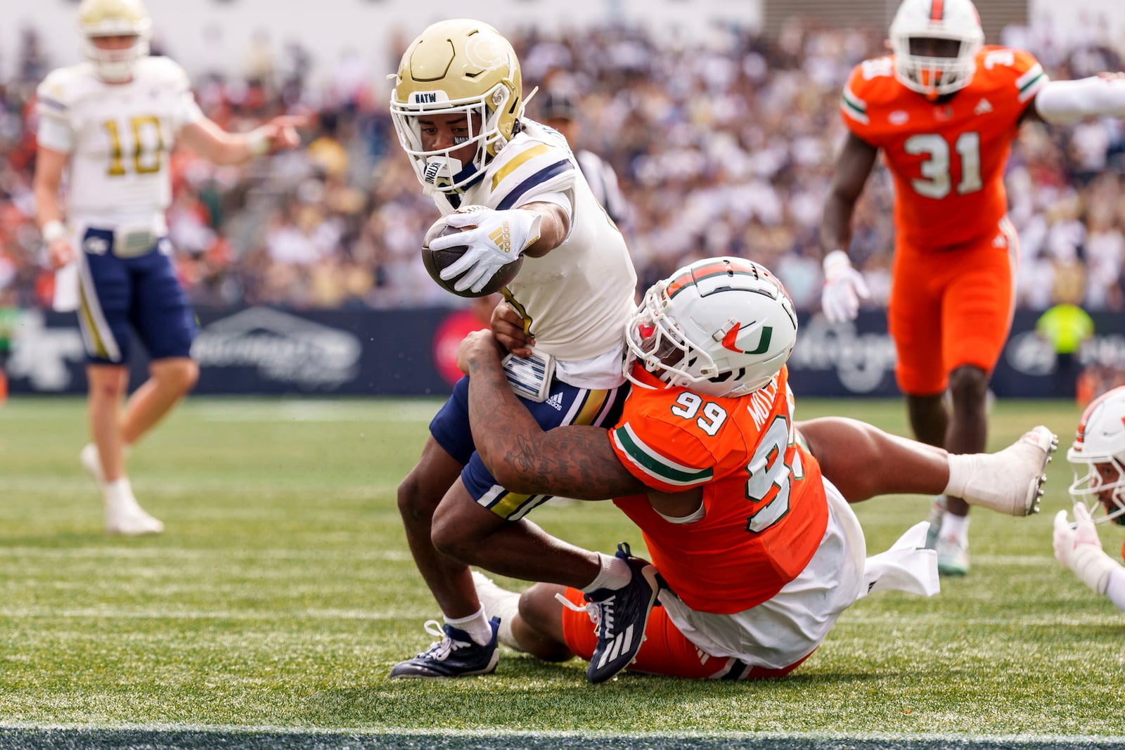 Georgia Tech wide receiver Malik Rutherford, left, reaches over the goal line while being tackled by Miami defensive lineman Ahmad Moten Sr. (99) during the first half of an NCAA college football game, Saturday, Nov. 9, 2024, in Atlanta. (AP Photo/Jason Allen)