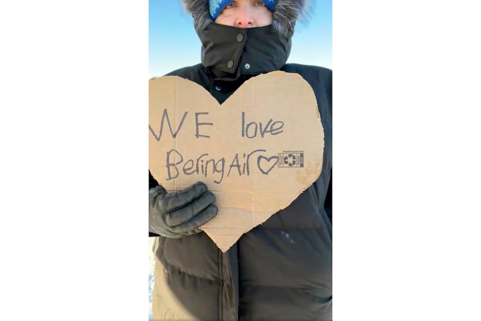 In this screen grab from a Facebook livestream, a resident of the Inupiat Eskimo village of Golovin in Alaska, holds a sign that says ‘We Love Bering Air’ on Saturday, Feb. 8, 2025. (AP via Irene Navarro)