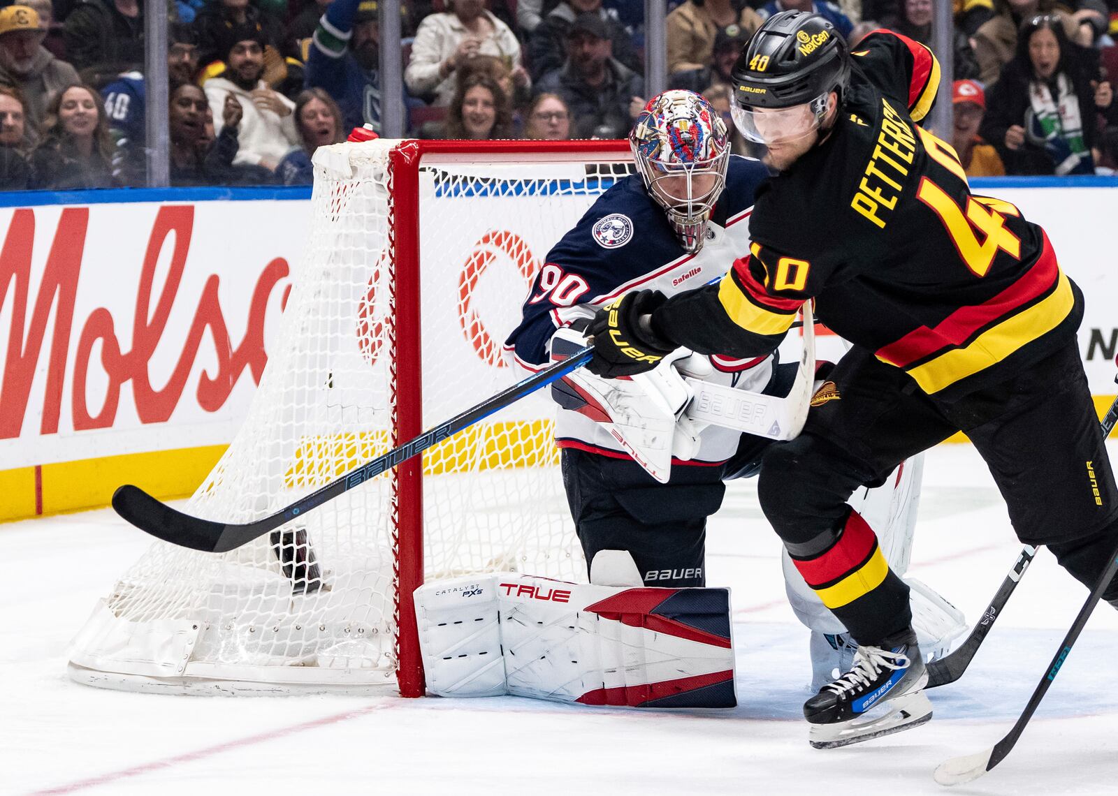 Columbus Blue Jackets goaltender Elvis Merzlikins (90) tries to stop Vancouver Canucks' Elias Pettersson (40) as he vies for the puck during the third period of an NHL hockey game in Vancouver, British Columbia, Friday, Dec. 6, 2024. (Ethan Cairns/The Canadian Press via AP)