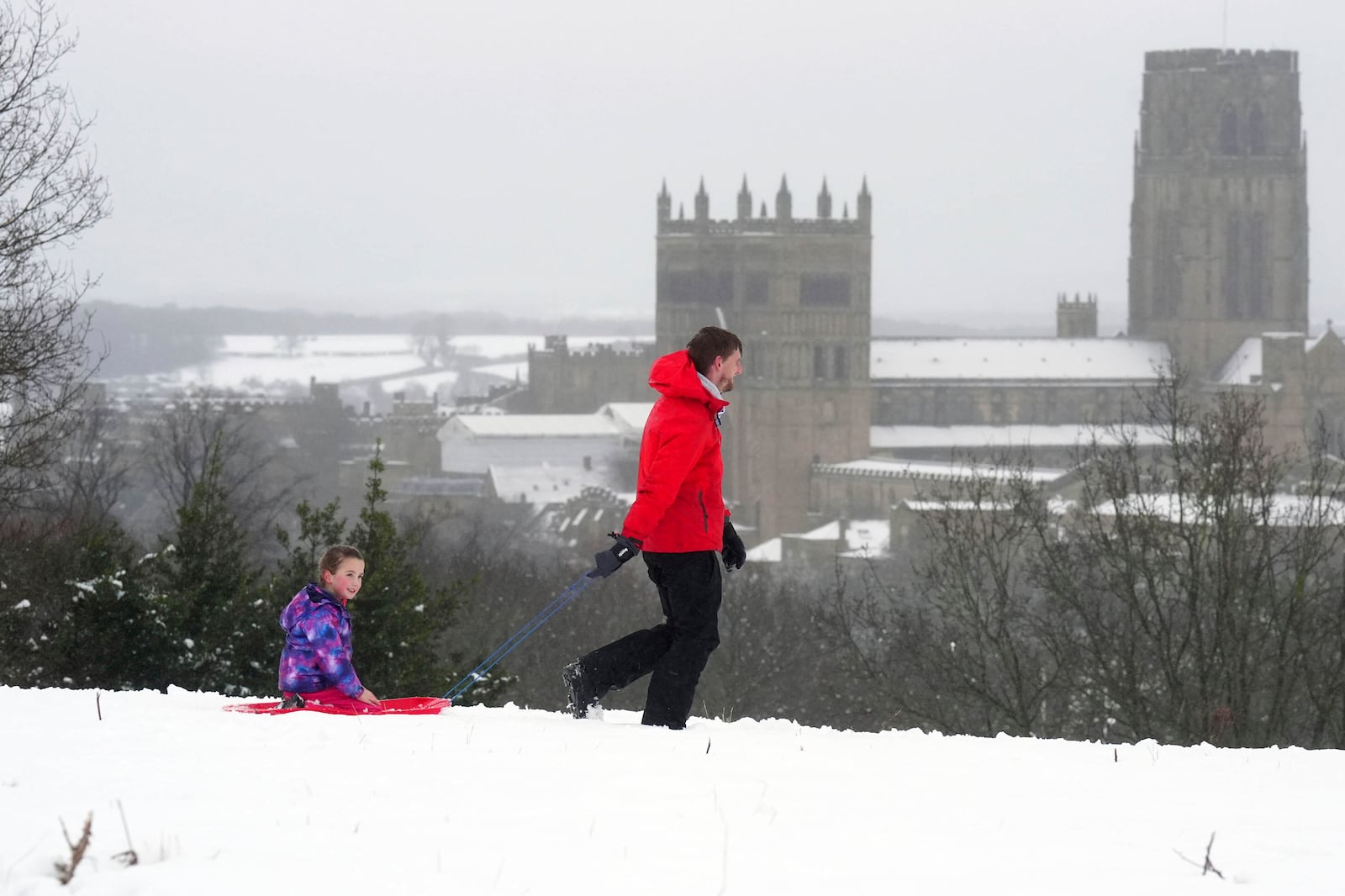 People sledging near Durham Cathedral in Durham, north England, Sunday Jan. 5, 2025, as heavy overnight snow causes disruption across the UK as the cold start to the new year continues. (Owen Humphreys/PA via AP)