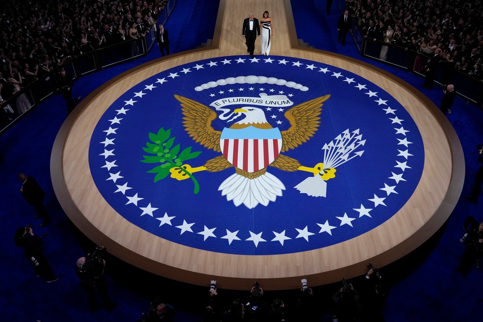 President Donald Trump, left, and first lady Melania Trump walk to the stage to dance at the Commander in Chief Ball, Monday, Jan. 20, 2025, in Washington. (AP Photo/Alex Brandon)