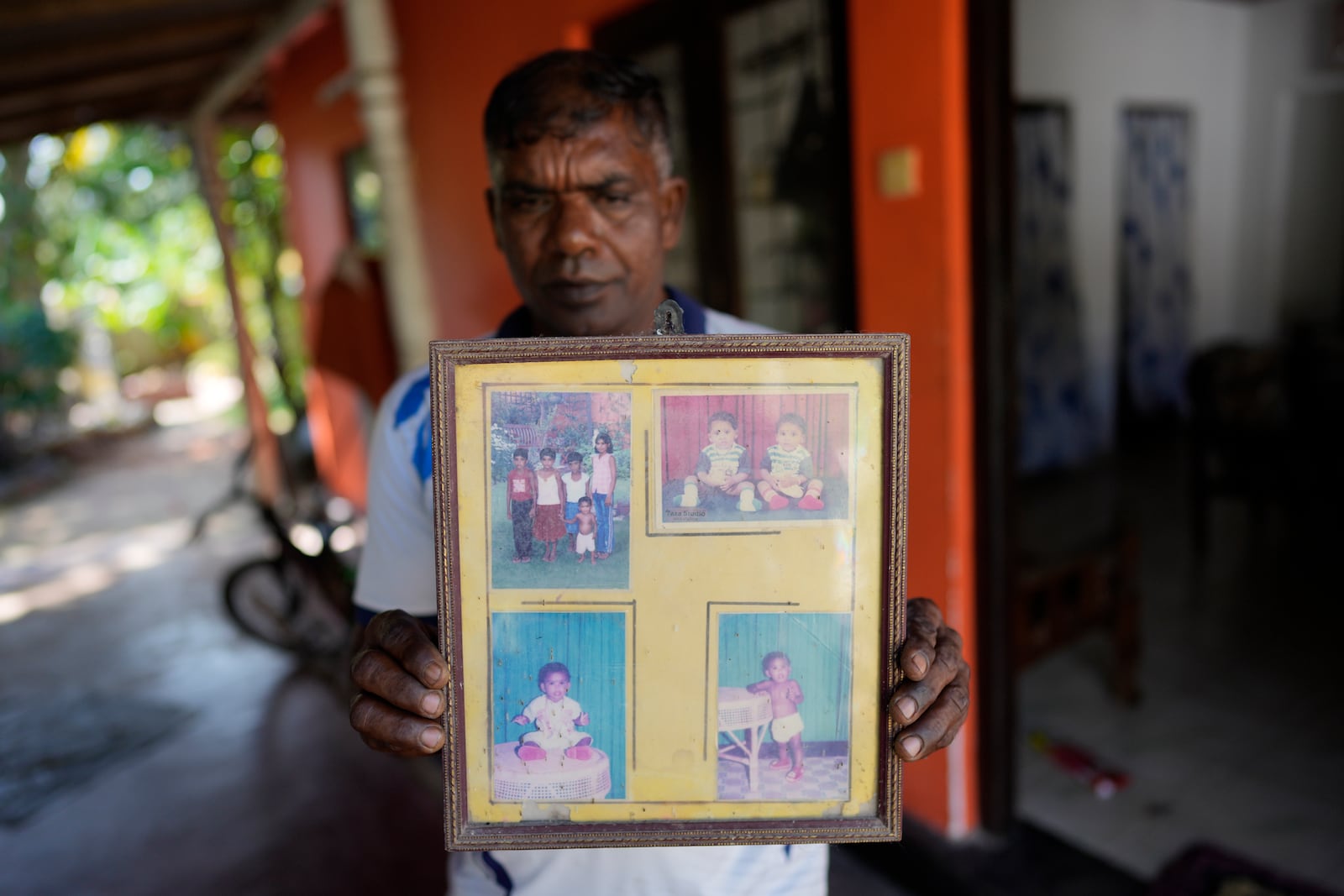 Tsunami survivor Kumudu Priyantha holds photographs of his three daughters and wife who died during 2004 Indian Ocean tsunami during its 20th anniversary in Peraliya, Sri Lanka, Thursday, Dec. 26, 2024. (AP Photo/Eranga Jayawardena)