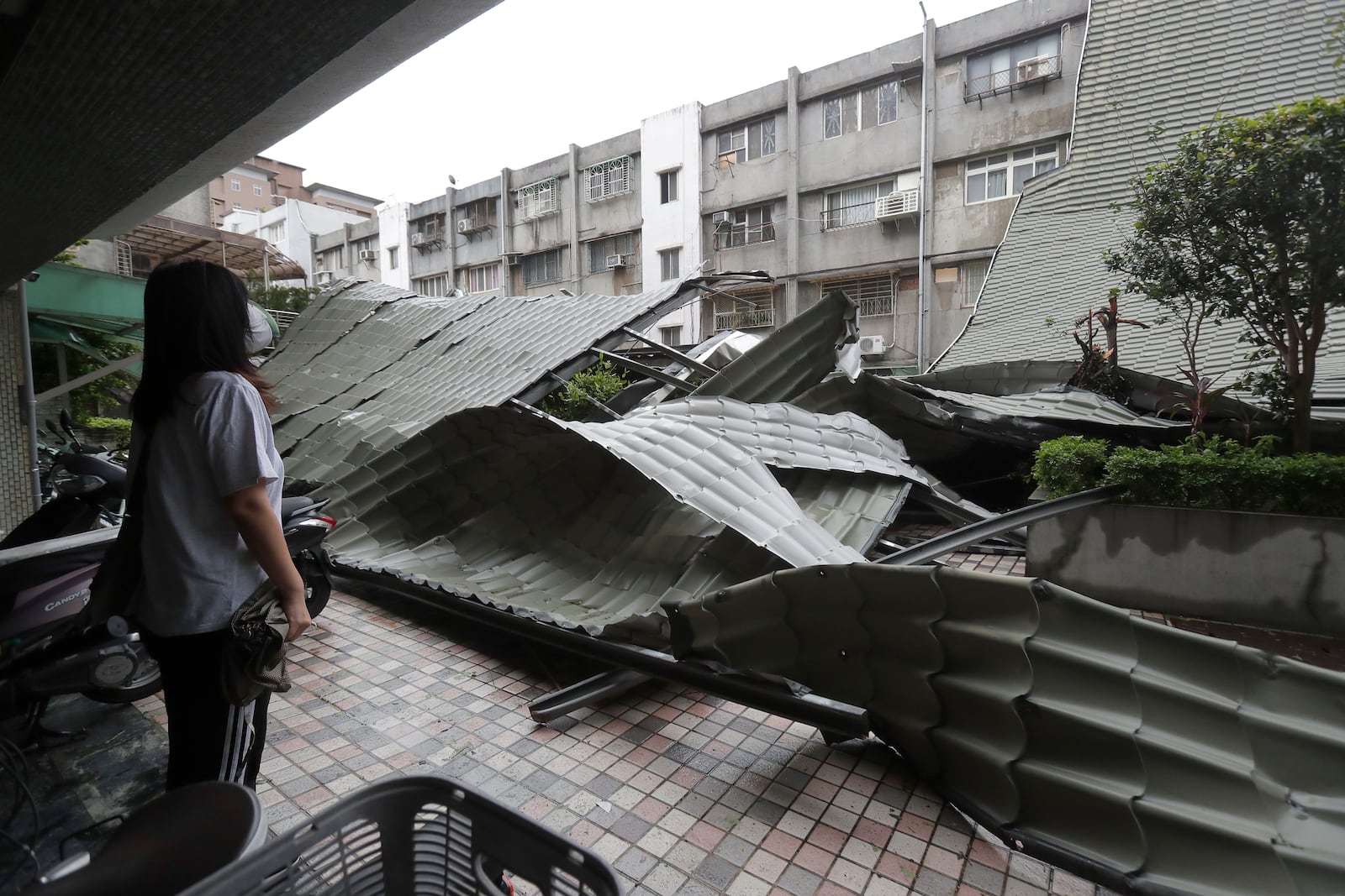 A woman looks at a row of blown roofs destroyed by the wind of Typhoon Kong-rey in Taipei, Taiwan, Friday, Nov. 1, 2024. (AP Photo/Chiang Ying-ying)