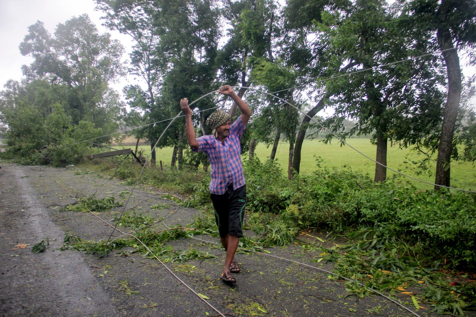 A man untangles fallen overhead cables on the coast of Bay of Bengal in Balasore district of Odisha state, on India's eastern coastline, where Tropical Storm Dana made landfall late Thursday night, according to the Indian Meteorological Department, India, Friday, Oct. 25, 2024. (AP Photo)