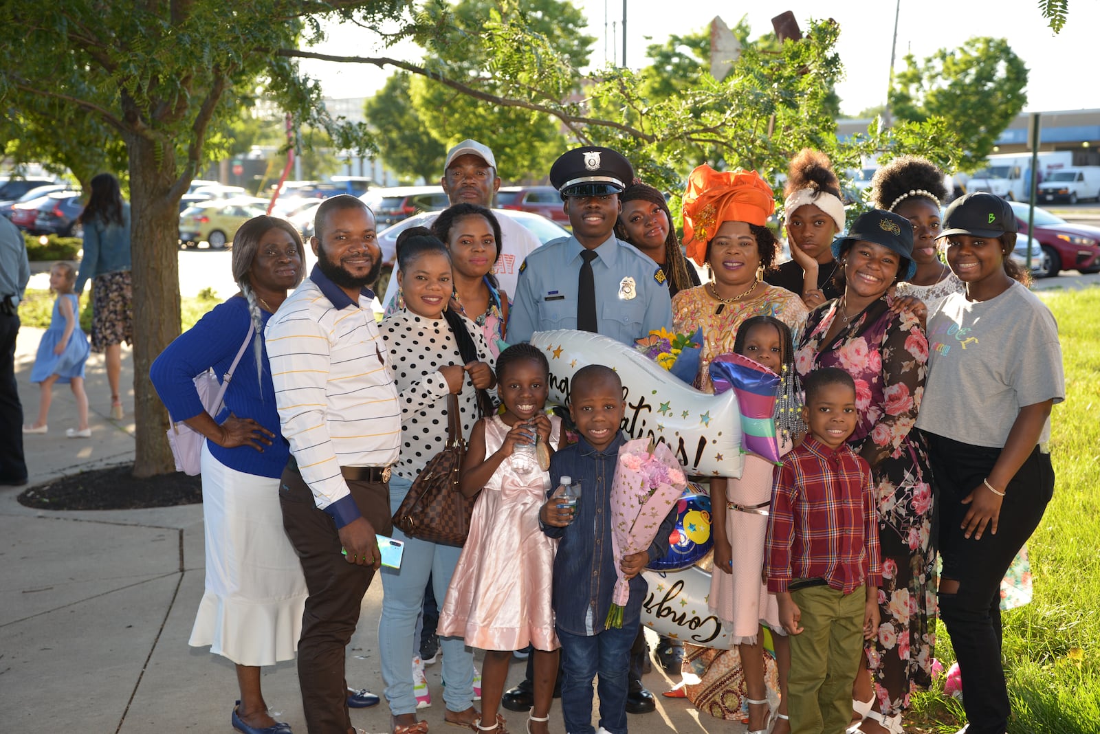 Newly graduated Dayton Police officer Bibebibyo “Bibe” Seko and his mom Sela (orange head wrap) surrounded by their family at Bibe’s graduation. (Photo by Gary Laughlin)