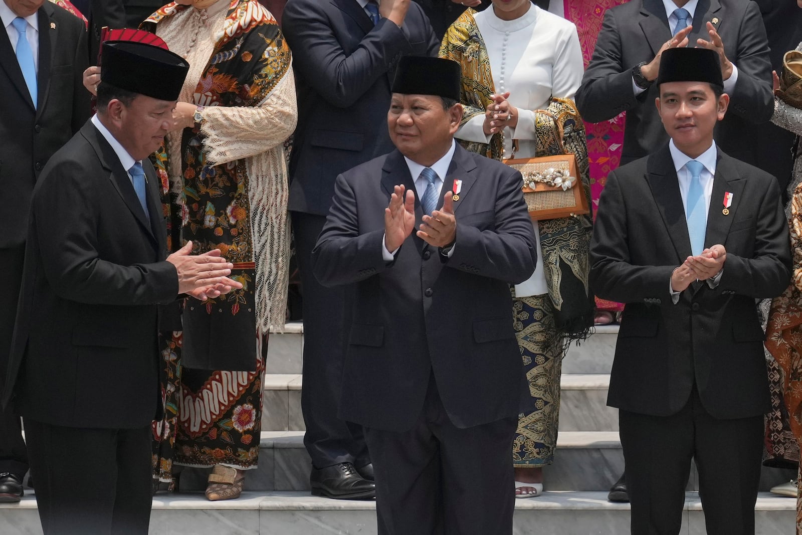 Indonesian President Prabowo Subianto, center, Vice President Gibran Rakabuming Raka, right, and Coordinating Minister for Political and Security Affairs Budi Gunawan, left, applaud after the swearing-in ceremony of the new cabinet ministers at Merdeka Palace in Jakarta, Indonesia, Monday, Oct. 21, 2024. (AP Photo/Achmad Ibrahim)