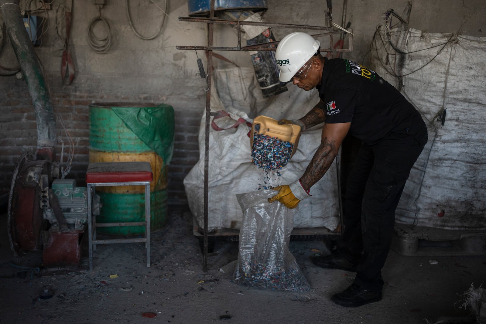 Jesus Cuevas, a Petgas technician, collects shredded plastic caps into a bag at a recycling center in Boca del Rio, Veracruz, Mexico, Jan. 4, 2025. (AP Photo/Felix Marquez)