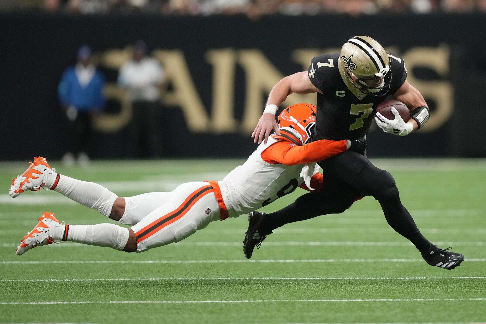 New Orleans Saints tight end Taysom Hill (7) is tackled by Cleveland Browns safety Grant Delpit, left, in the first half of an NFL football game in New Orleans, Sunday, Nov. 17, 2024. (AP Photo/Gerald Herbert)