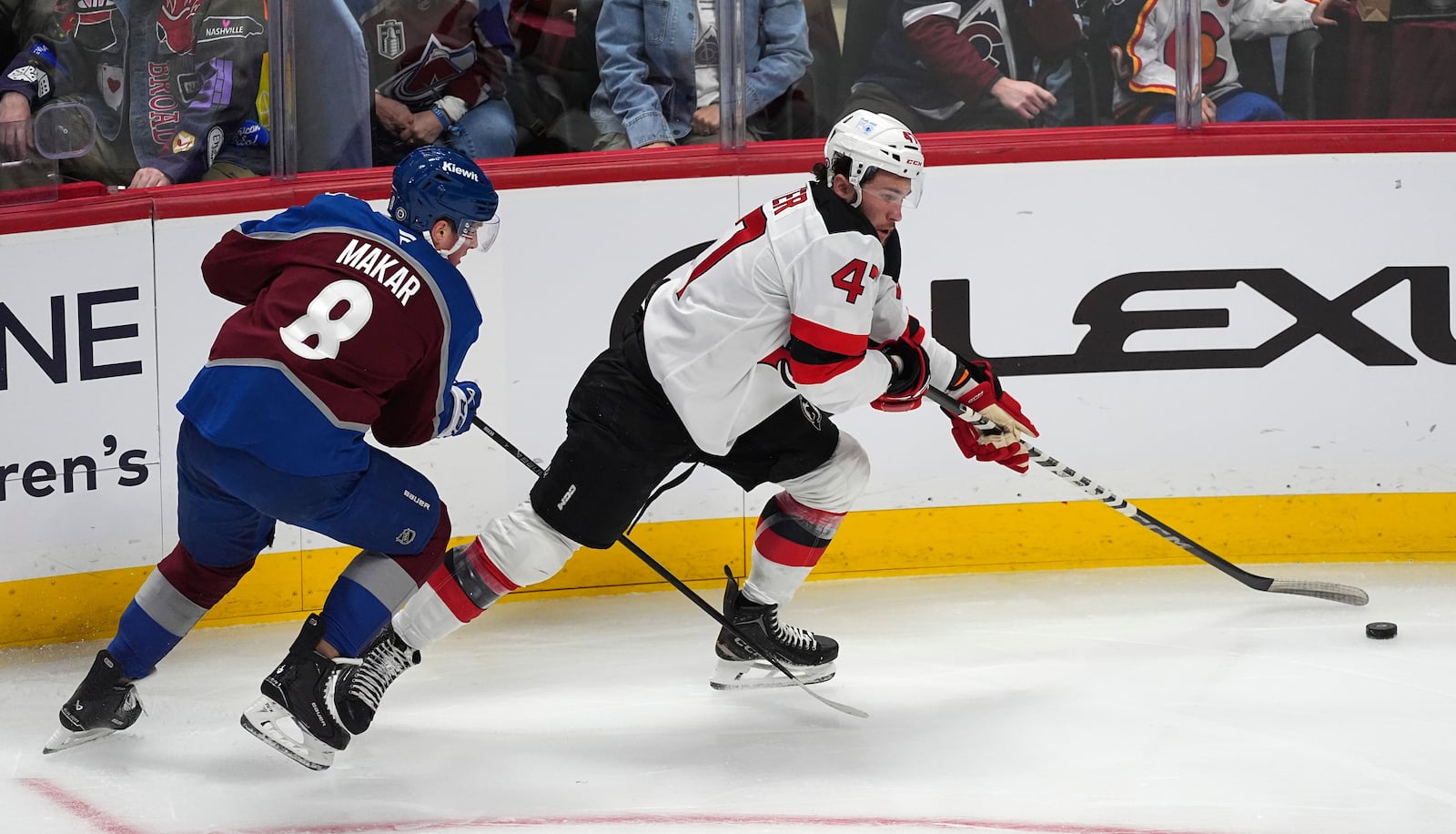 New Jersey Devils center Paul Cotter, right, collects the puck as Colorado Avalanche defenseman Cale Makar covers in the first period of an NHL hockey game Wednesday, Feb. 26, 2025, in Denver. (AP Photo/David Zalubowski)