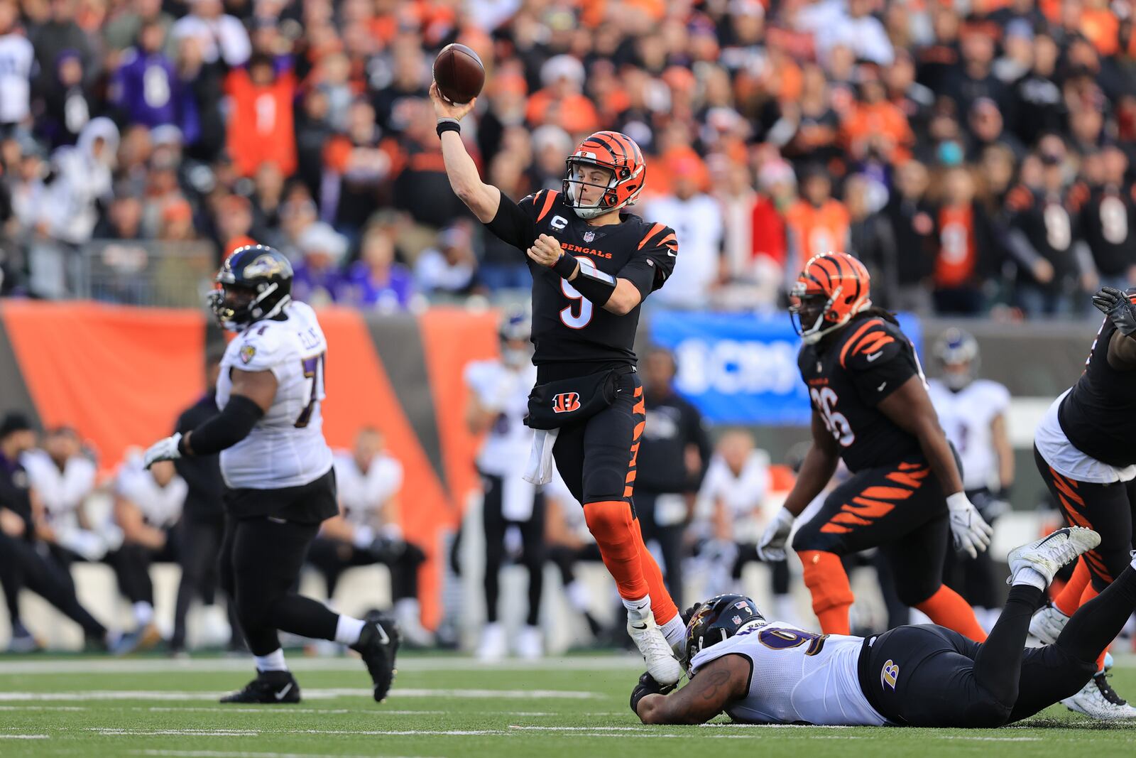 Cincinnati Bengals quarterback Joe Burrow (9) throws while being tackled by Baltimore Ravens' Broderick Washington during the second half of an NFL football game, Sunday, Dec. 26, 2021, in Cincinnati. (AP Photo/Aaron Doster)