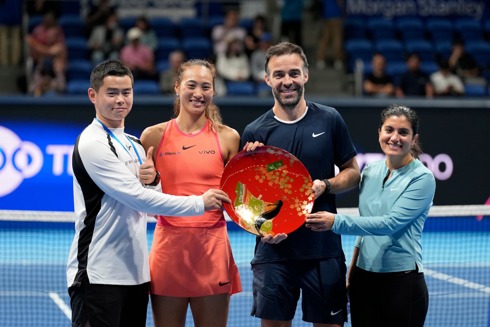 China's Zheng Qinwen and her supporting team pose with the trophy after she won the Pan Pacific Open women's tennis tournament at Ariake Coliseum, in Tokyo, Sunday, Oct. 27, 2024. (AP Photo/Eugene Hoshiko)