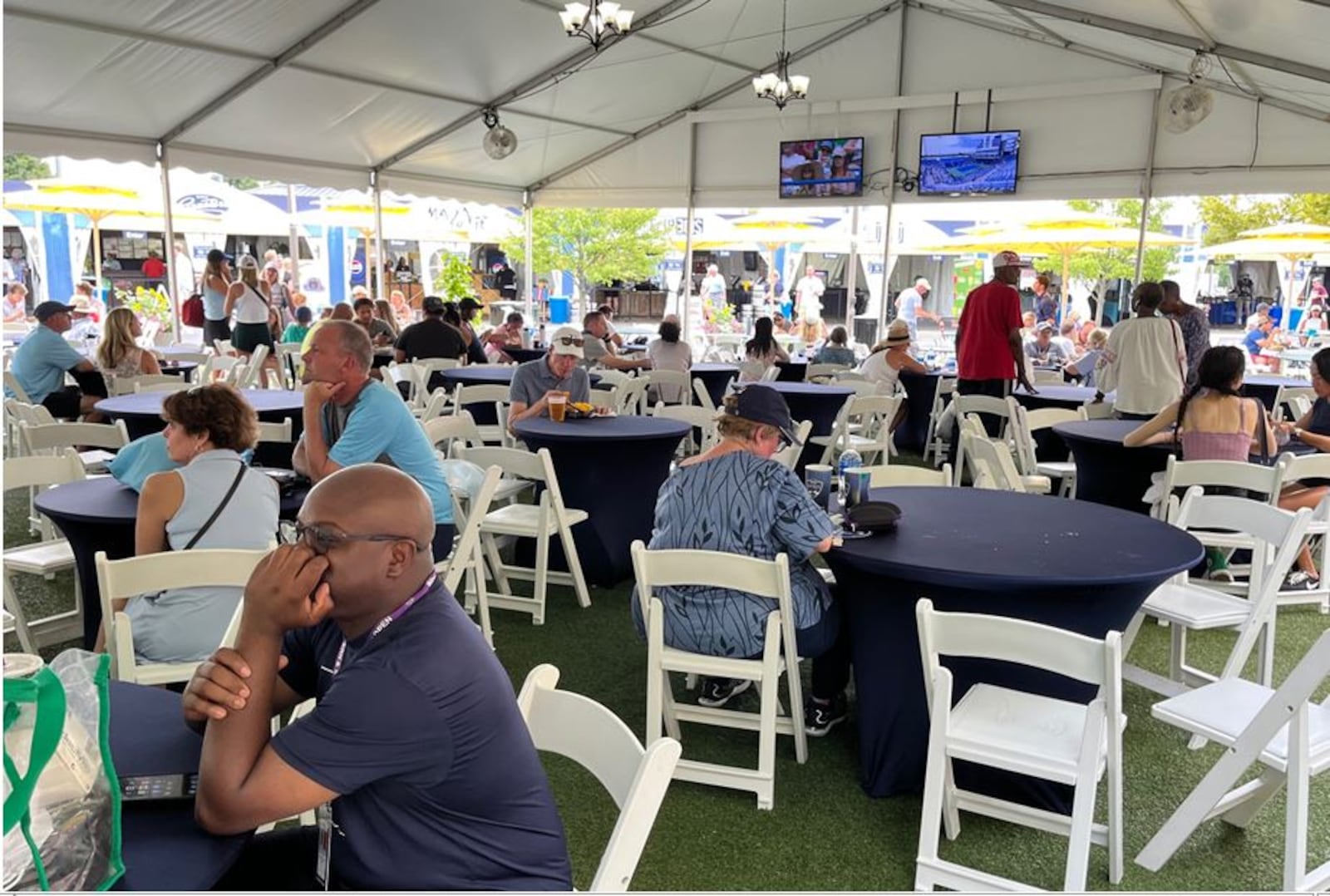 Tennis fans can watch the tennis action on monitors in one of several pavilions that have tables and chairs as they enjoy food and beverages at the Western & Southern Open in Mason.  ED RICHTER/STAFF