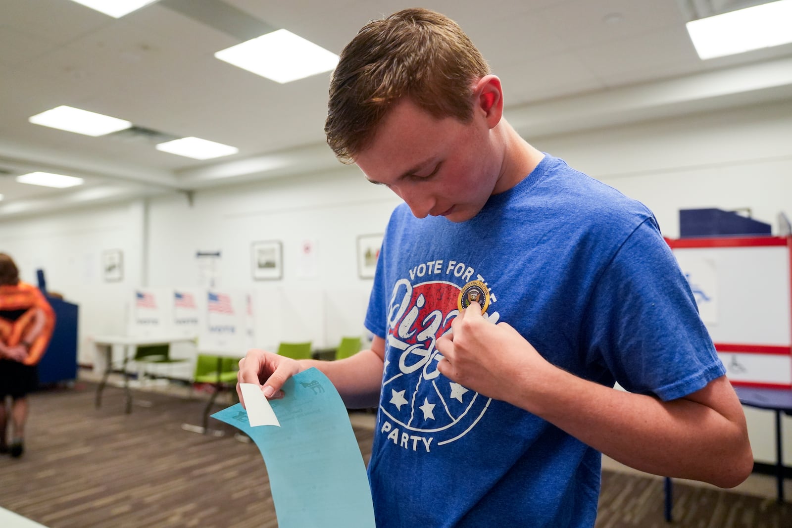 First-time voter Ethan Stregack, 18, places a sticker on his shirt after casting his ballot, Thursday, Oct. 31, 2024, in Falls Church, Va. (AP Photo/Stephanie Scarbrough)