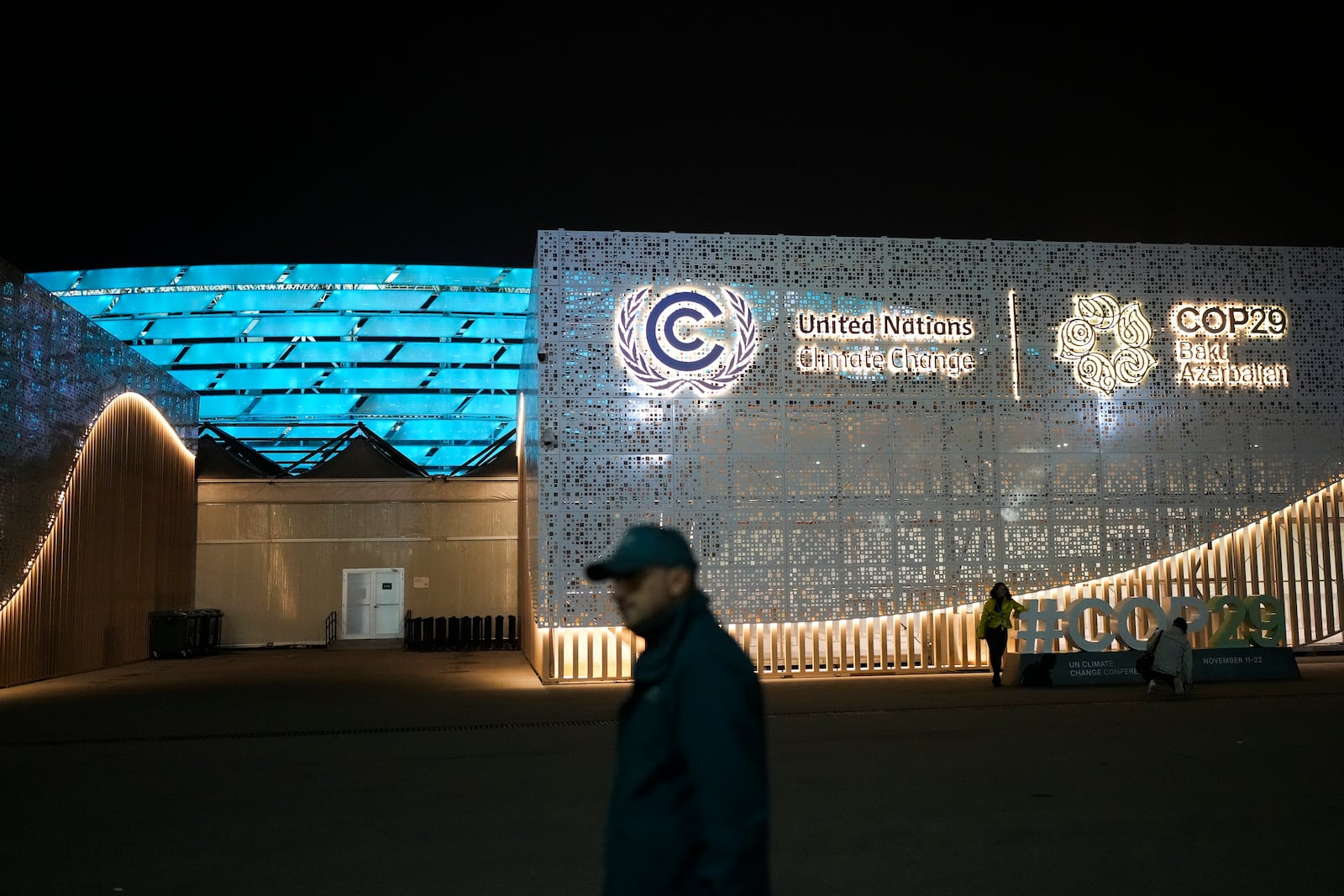 People walk outside the venue for the COP29 U.N. Climate Summit, Monday, Nov. 11, 2024, in Baku, Azerbaijan. (AP Photo/Rafiq Maqbool)