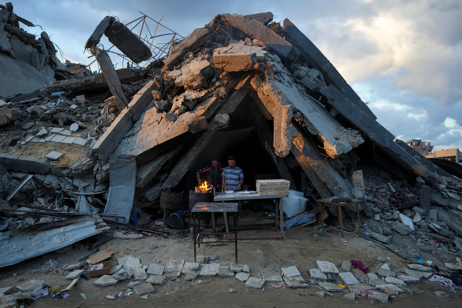 A man sells bread under the destruction of his bakery destroyed by the Israeli air and ground offensive in Jabaliya, Gaza Strip, Wednesday, Feb. 5, 2025. (AP Photo/Abdel Kareem Hana)