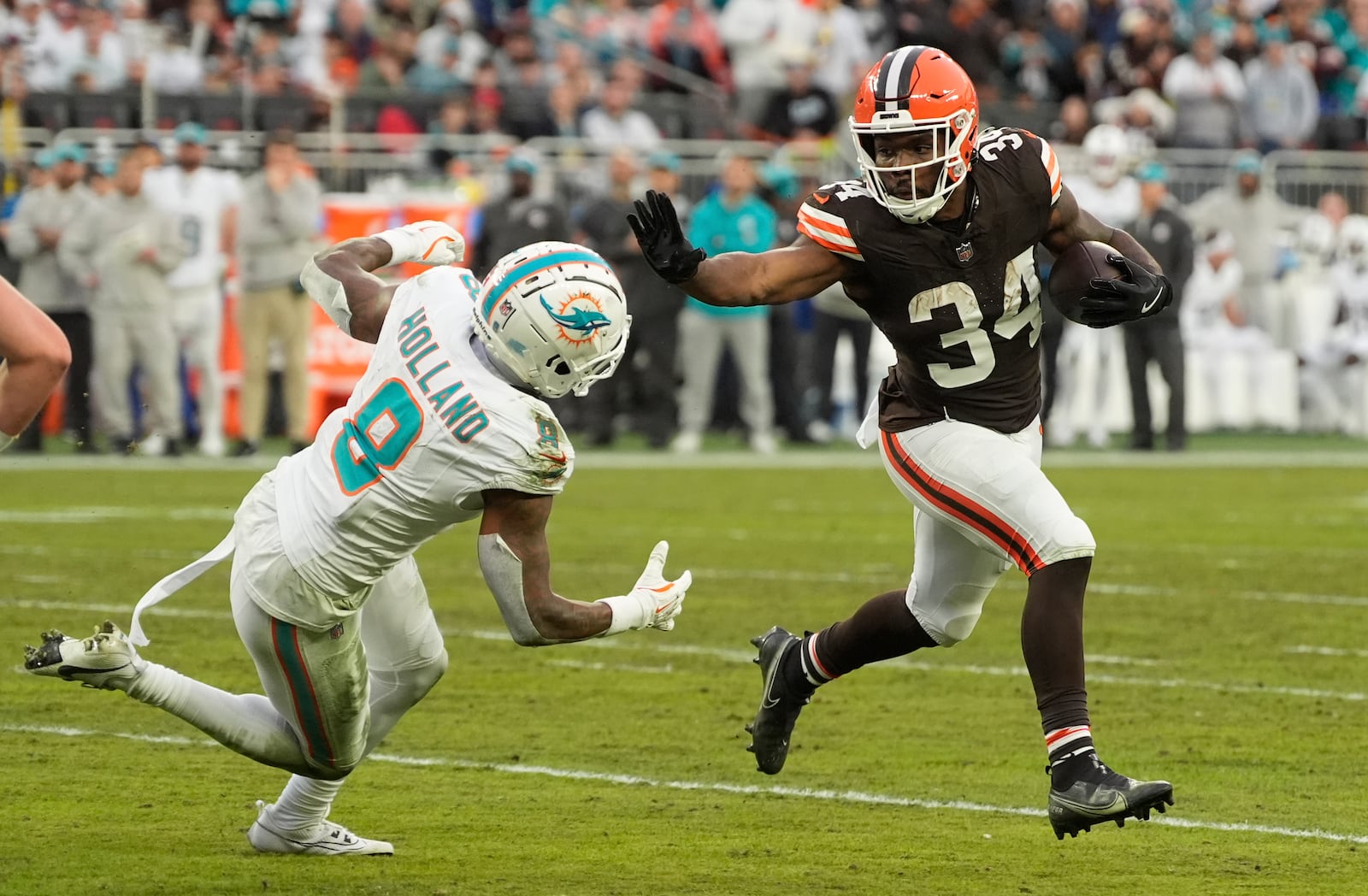 Cleveland Browns running back Jerome Ford (34) runs as Miami Dolphins safety Jevon Holland (8) defends during the first half of an NFL football game Sunday, Dec. 29, 2024, in Cleveland. (AP Photo/Sue Ogrocki)