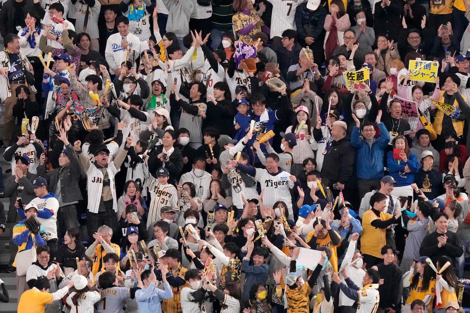 Fans cheer after Hanshin Tigers' Teruaki Sato hit a three-run home run during the fourth inning in an MLB Japan Series exhibition baseball game between the Los Angeles Dodgers and the Tigers, Sunday, March 16, 2025, in Tokyo. (AP Photo/Eugene Hoshiko)