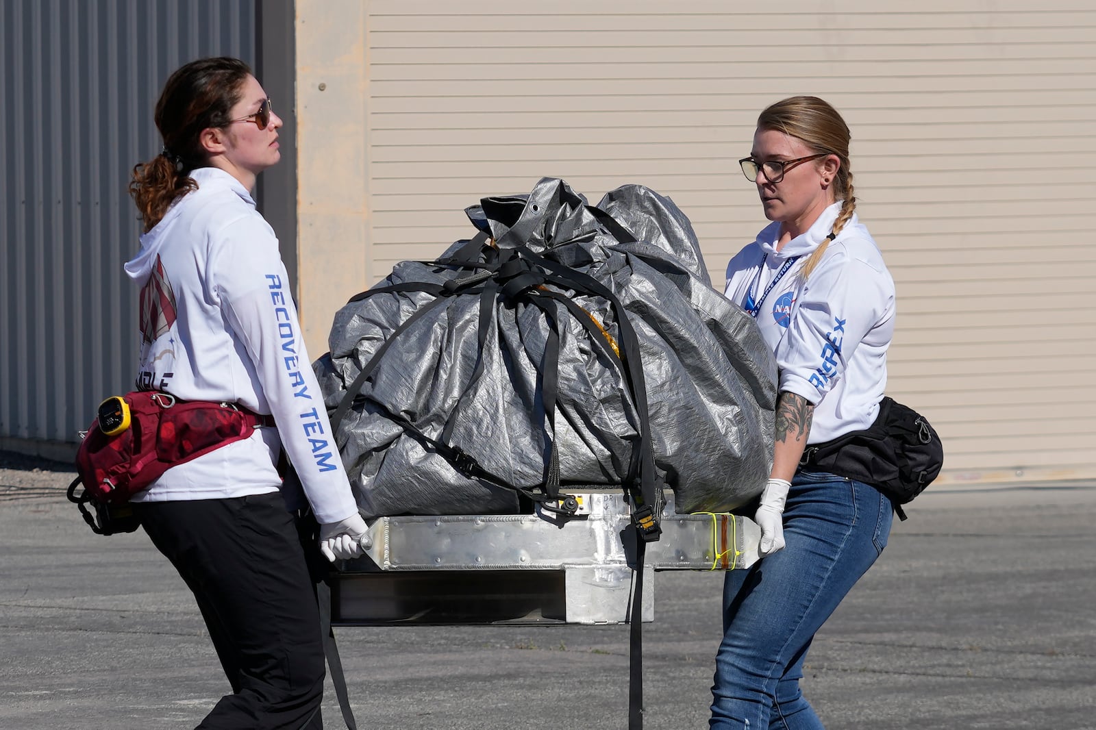 FILE - Recovery team members carry a capsule containing NASA's first asteroid samples to a temporary clean room at Dugway Proving Ground in Utah on Sept. 24, 2023. (AP Photo/Rick Bowmer, Pool, file)