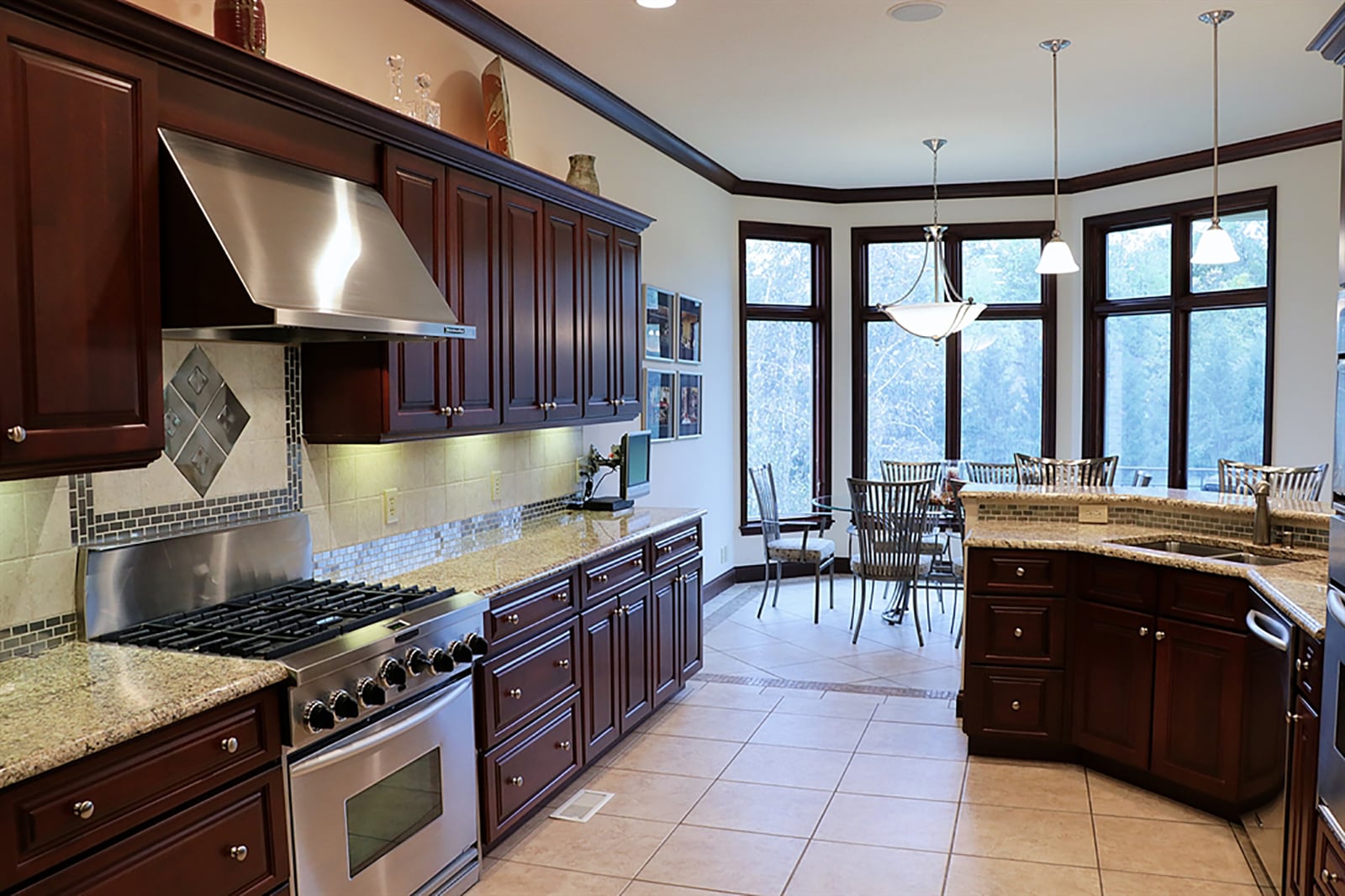 A bay-like breakfast room is offset from the kitchen by a 2-level peninsula countertop. The upper counter creates a breakfast bar setting for up to four while the lower level has a double sink and additional work space. Cherry cabinetry fills two walls of the kitchen and surrounds stainless-steel appliances. CONTRIBUTED PHOTO BY KATHY TYLER