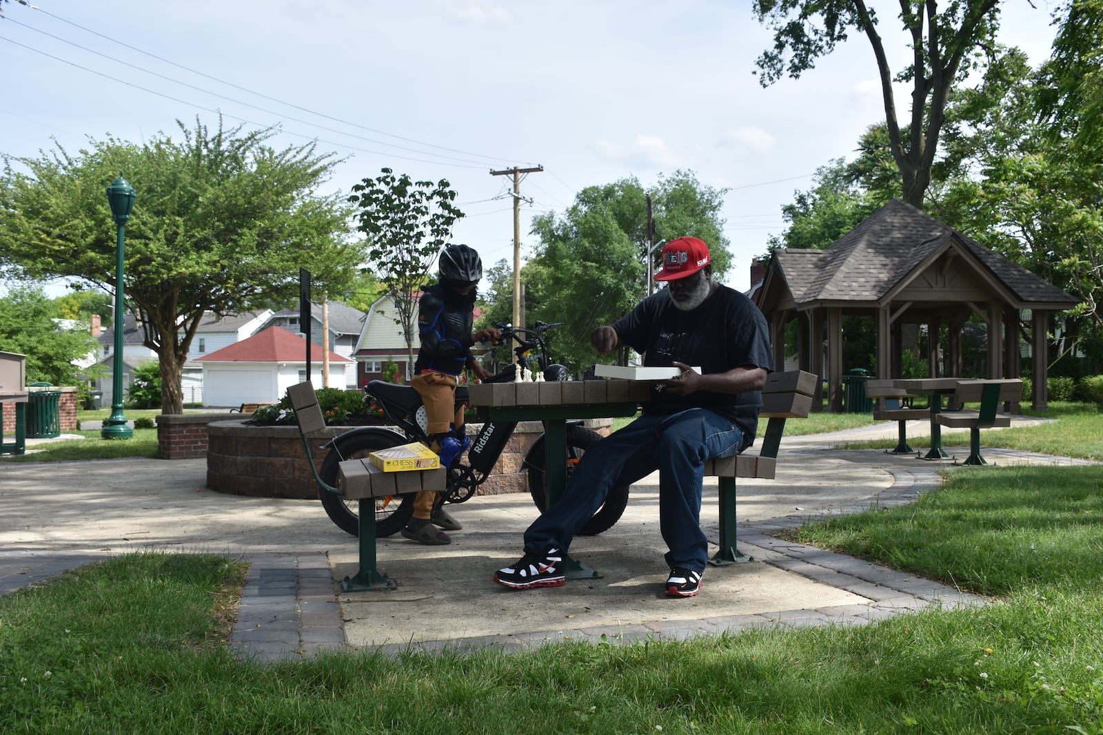 Iran Johnson, 51, puts chess pieces out on a table at Carrick's Corner Pocket Park, located at 300 Delaware Ave. in northwest Dayton. Edjuan Campbell, 12, rode his bike to the park. CORNELIUS FROLIK / STAFF