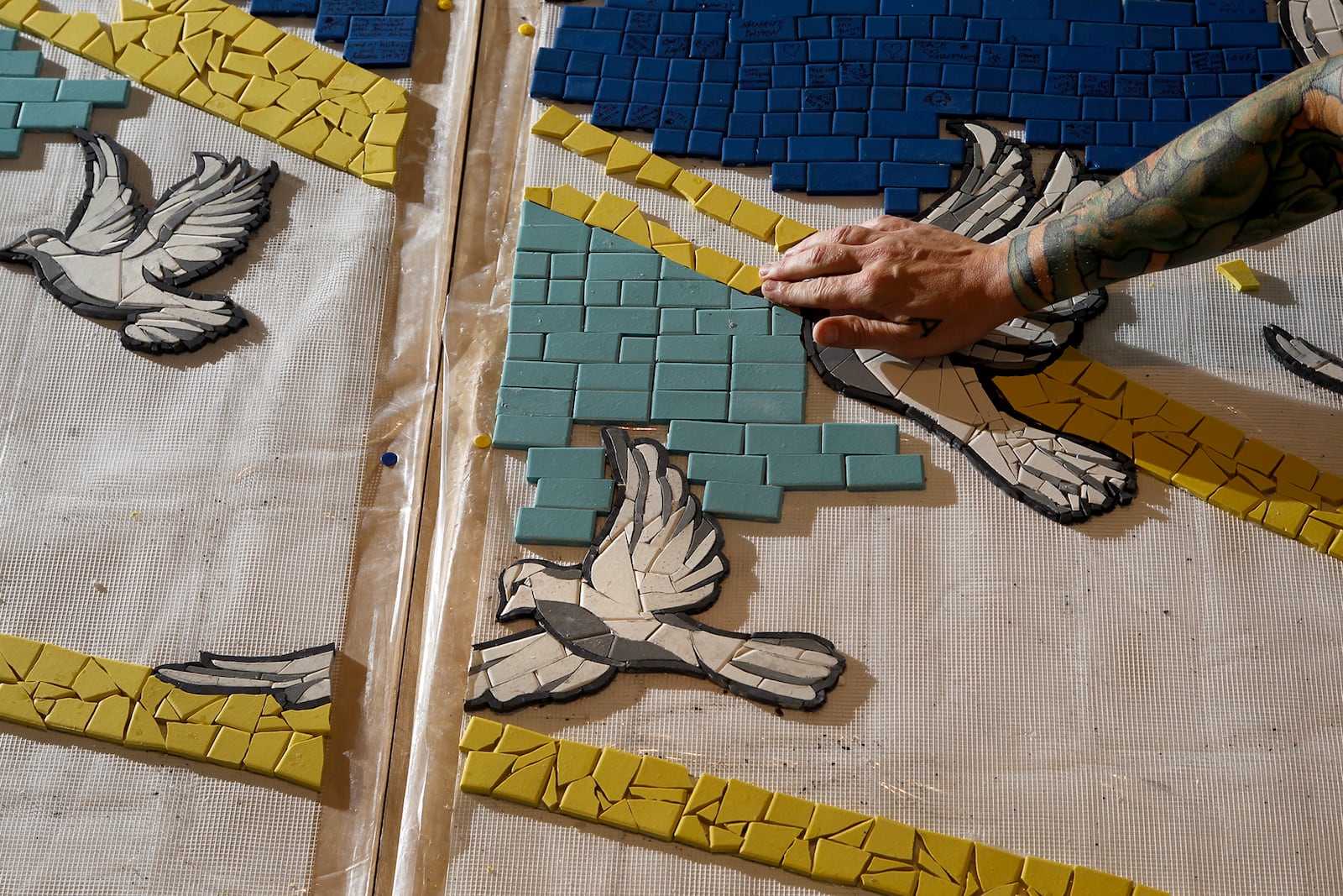 Jes McMillan, founder of The Mosaic Institute of Greater Dayton, along with her staff, designed a mosaic mural, "9 Doves," to commemorate the nine people killed in the Oregon District shooting.  LISA POWELL / STAFF