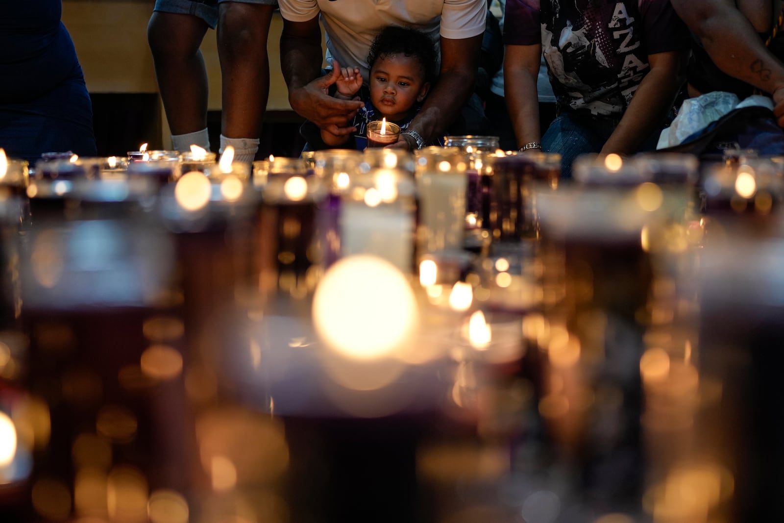 Reinaldo Almanza holds his son Reinier with a candle at San Felipe Church in honor of the Black Christ in Portobelo, Panama, Monday, Oct. 21, 2024, during a festival celebrating the iconic statue that was found on the shore in 1658. (AP Photo/Matias Delacroix)