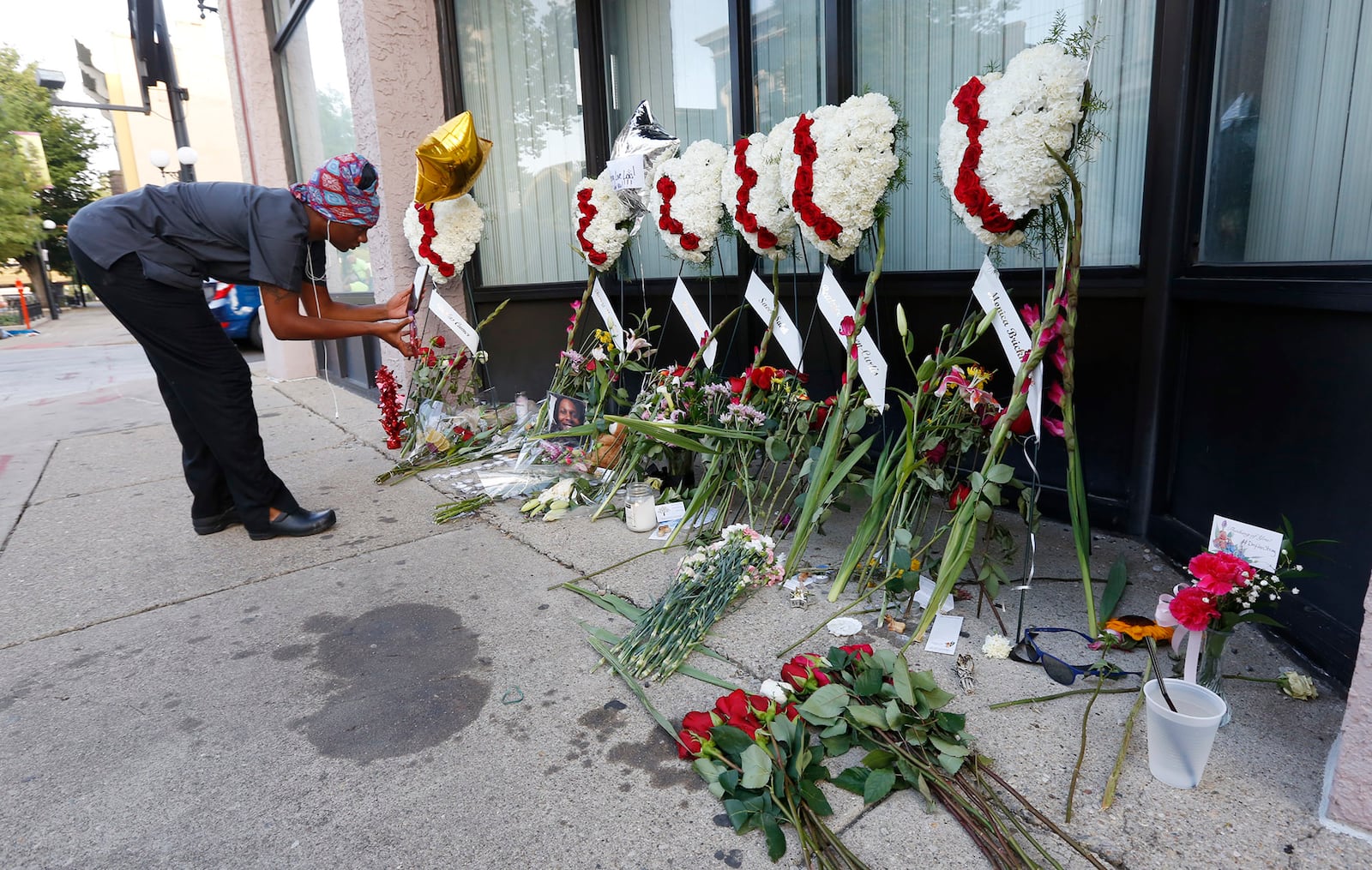 Cierra Mallory takes video of a memorial to her friend Thomas “TJ” McNichols on the sidewalk of East Fifth Street on Tuesday morning. McNichols was one of nine people gunned down early Sunday morning in the Oregon District. TY GREENLEES / STAFF