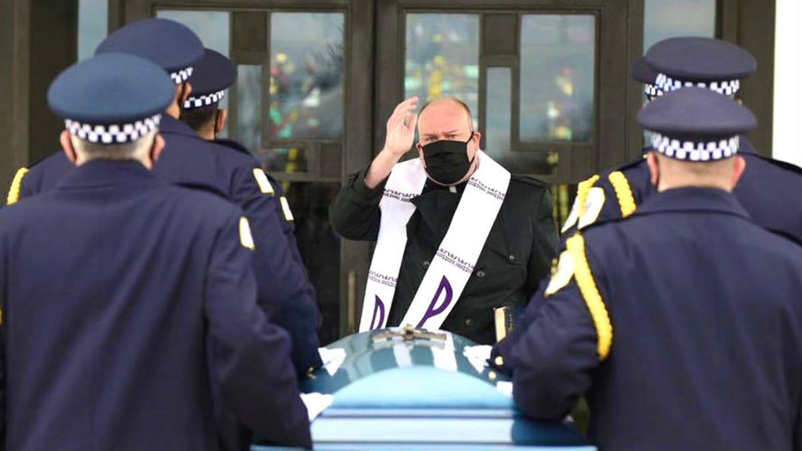 A priest wearing personal protective gear blesses the casket holding Chicago police Officer Marco DiFranco at the officer’s April 9, 2020, funeral. DiFranco, a narcotics officer, died April 2 of COVID-19, the illness caused by the novel coronavirus. (Chicago Police Department)