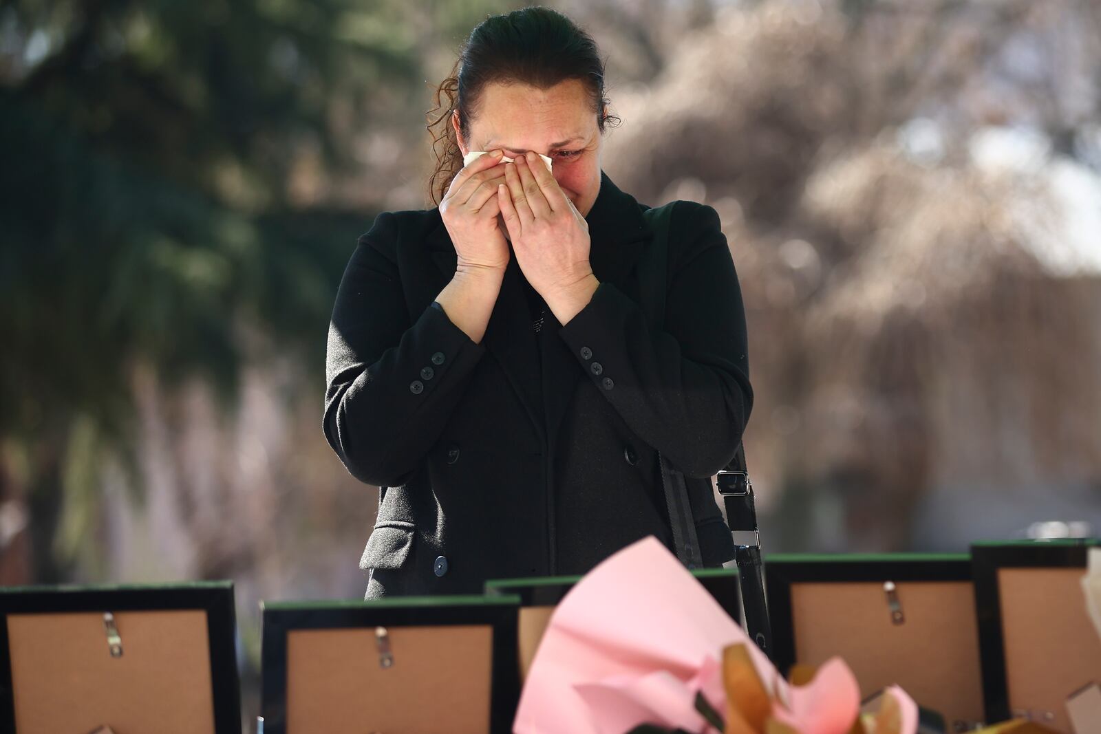 A woman cries looking at hotographs of the victims of a massive nightclub fire, placed in a square in the town of Kocani, North Macedonia, Thursday, March 20, 2025. (AP Photo/Armin Durgut)