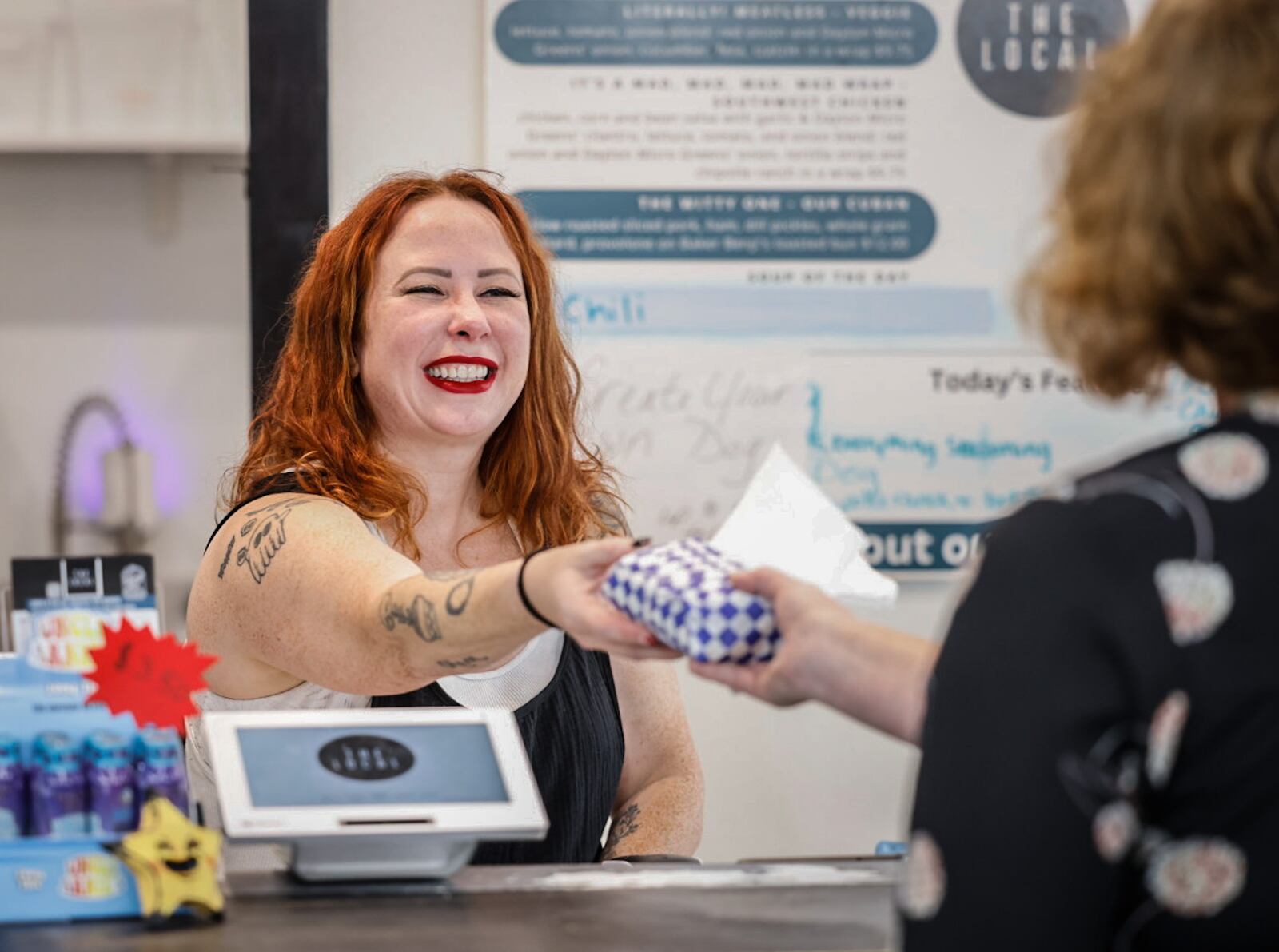 Rachel Gannon, owner of The Local 937 on Fifth Street in the St. Anne's Hill district,  delivers a sandwich to a customer Wednesday September 25, 2024. JIM NOELKER/STAFF