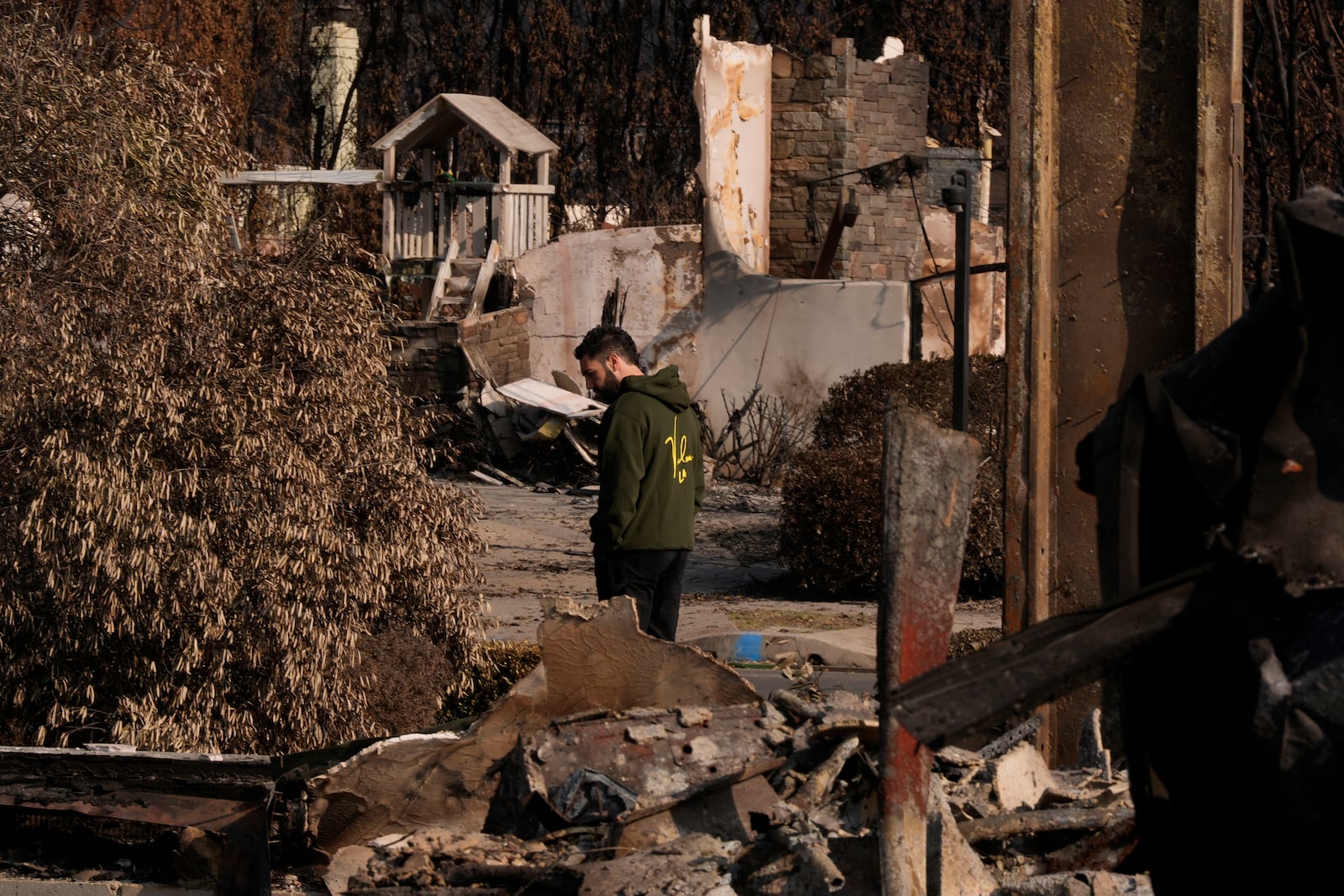 World Central Kitchen Chef Corp member Daniel Shemtob walks through the rubble of what remains of his home and his neighbor's homes destroyed by the Palisades Fire, Sunday, Jan. 19, 2025, in the Pacific Palisades neighborhood of Los Angeles, Calif. (AP Photo/Carolyn Kaster)