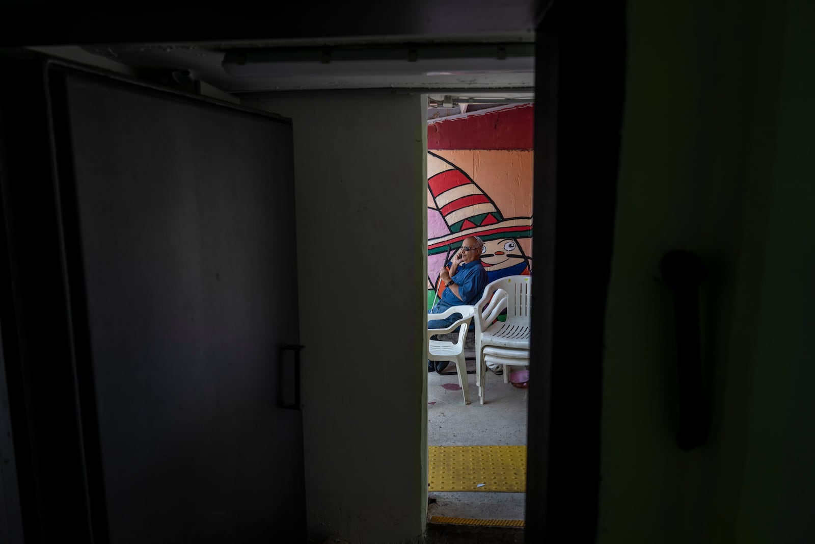 A man speaks on the phone in a public bomb shelter to stay safe from rockets fired from Lebanon in Acre, northern Israel, Sunday, Oct. 13, 2024. (AP Photo/Ariel Schalit)