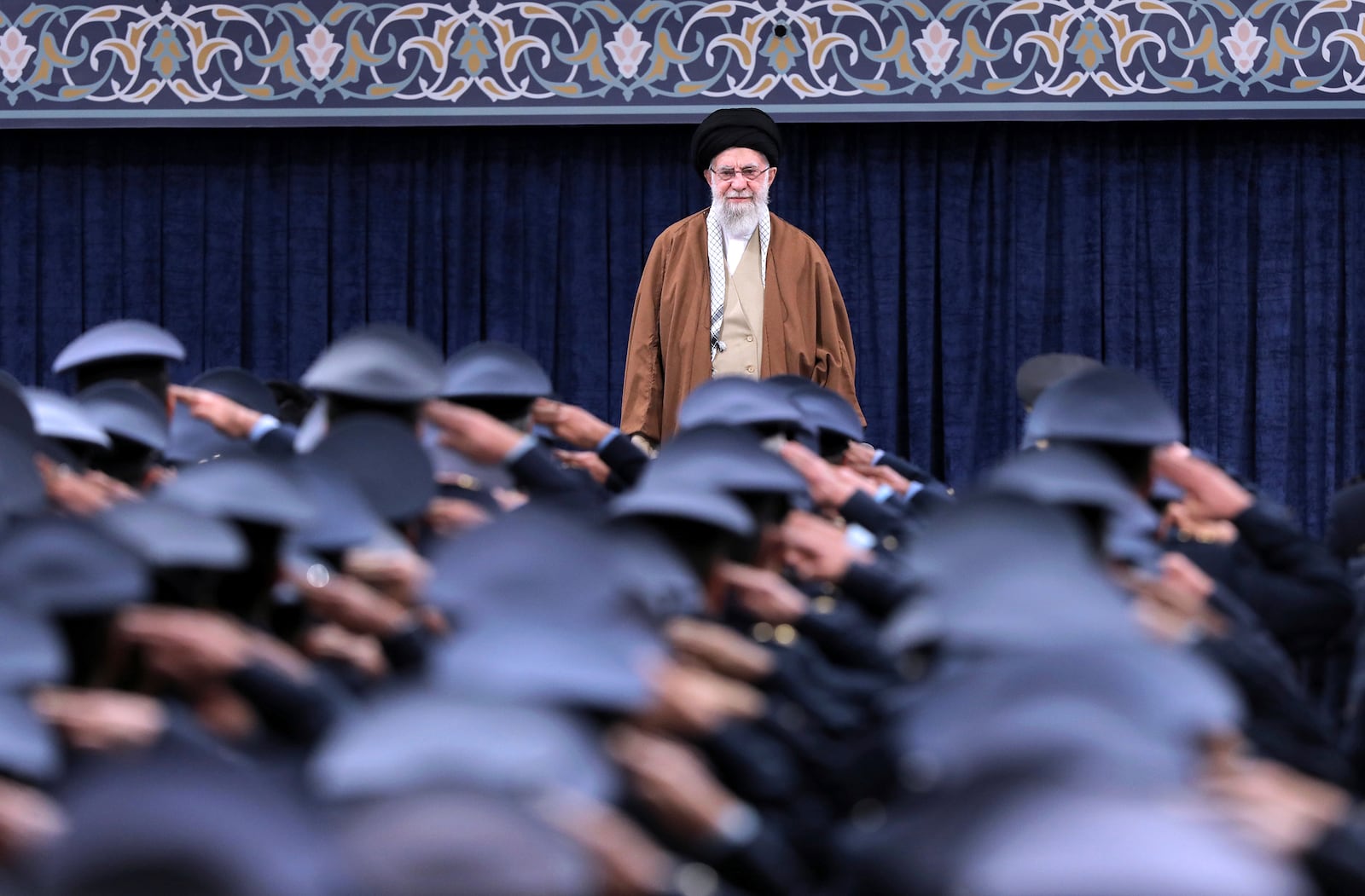 In this photo released by an official website of the office of the Iranian supreme leader, Supreme Leader Ayatollah Ali Khamenei listens to the national anthem as air force officers salute during their meeting in Tehran, Iran, Friday, Feb. 7, 2025. (Office of the Iranian Supreme Leader via AP)