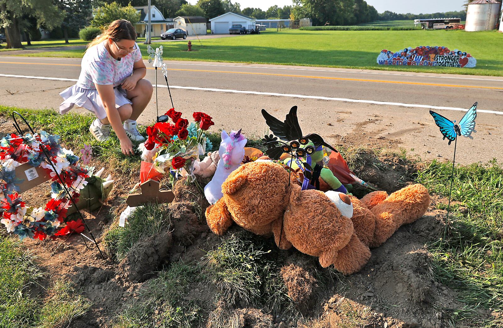 Madison Donnelly, a Northwestern Schools alumni, places flowers Wednesday, August 23, 2023 at a memorial along Troy Road at the site of Tuesday's fatal bus crash. BILL LACKEY/STAFF