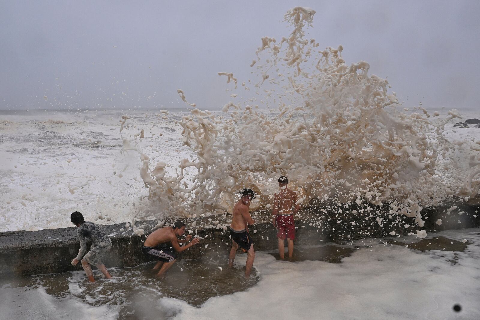 Children take shelter from waves behind a breakwall in the Coolangatta area of Gold Coast, Australia, Friday, March 7, 2025. (Dave Hunt/AAP Image via AP)