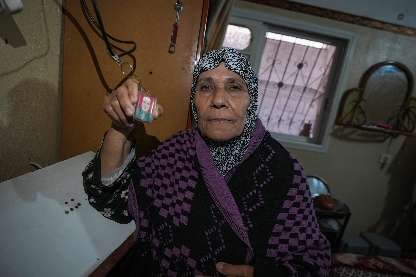 Sabah Alghrabli shows a key chain with a picture of her husband, Mahmoud Alghrabli, at her home in Khan Younis, Gaza Strip, Nov. 21, 2024. (AP Photo/Abdel Kareem Hana)