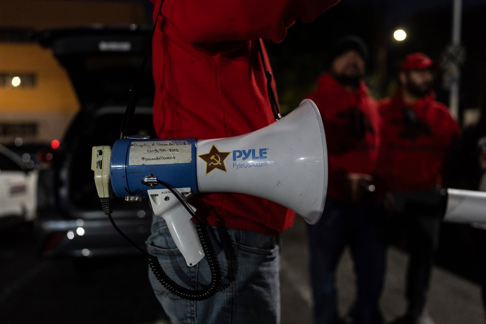 Ron Gochez, a teacher volunteering with Union del Barrio, an organization advocating for immigrant rights, carries a megaphone while speaking with other volunteers before searching for ICE activity in Los Angeles Thursday, Feb. 27, 2025. (AP Photo/Jae C. Hong)