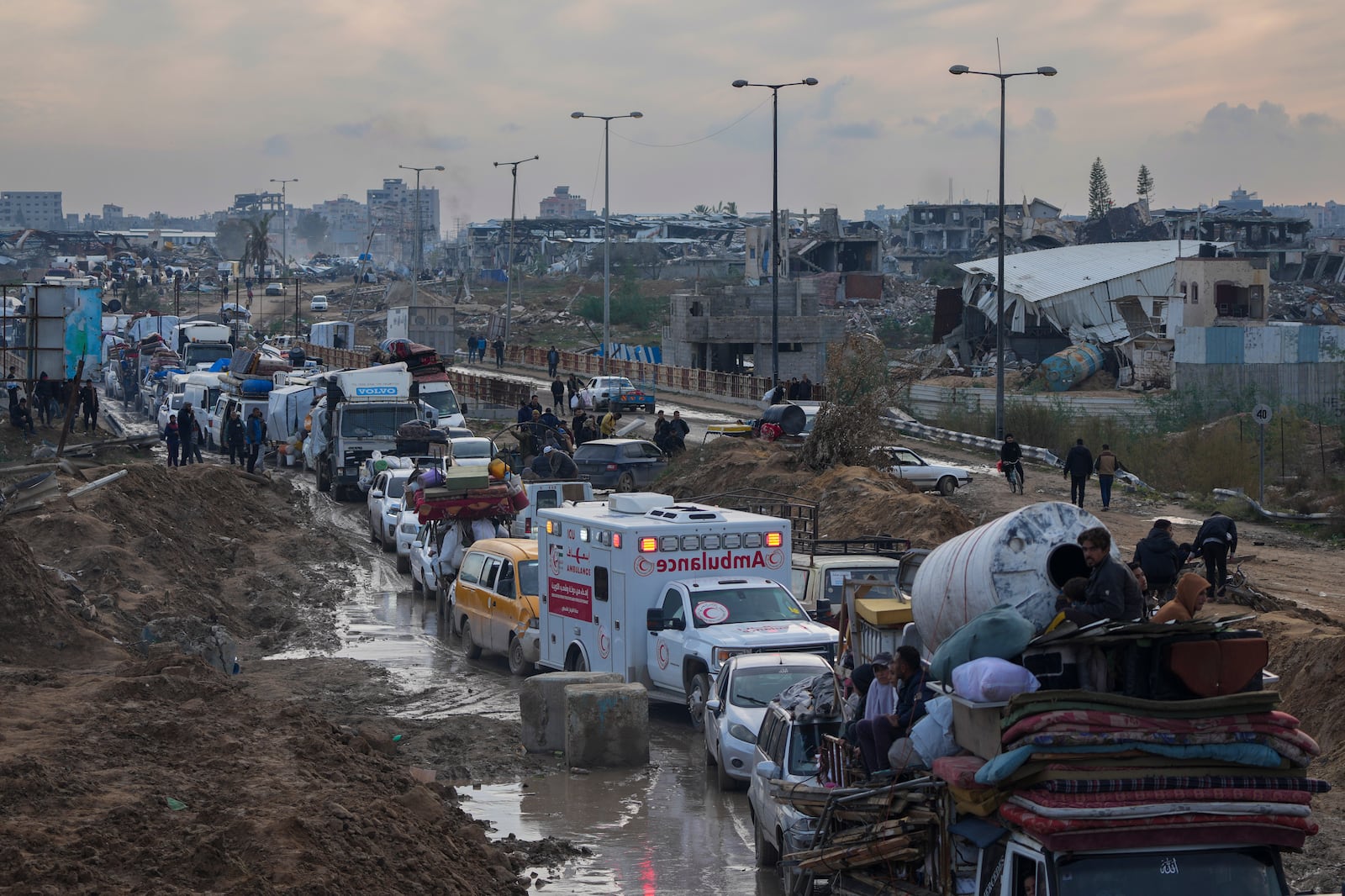 Displaced Palestinians, carrying their belongings in vehicles, wait at a security checkpoint in the Netzarim corridor while traveling from central Gaza to their homes in the northern Gaza Strip, Tuesday, Feb. 11, 2025. (AP Photo/Abdel Kareem Hana)